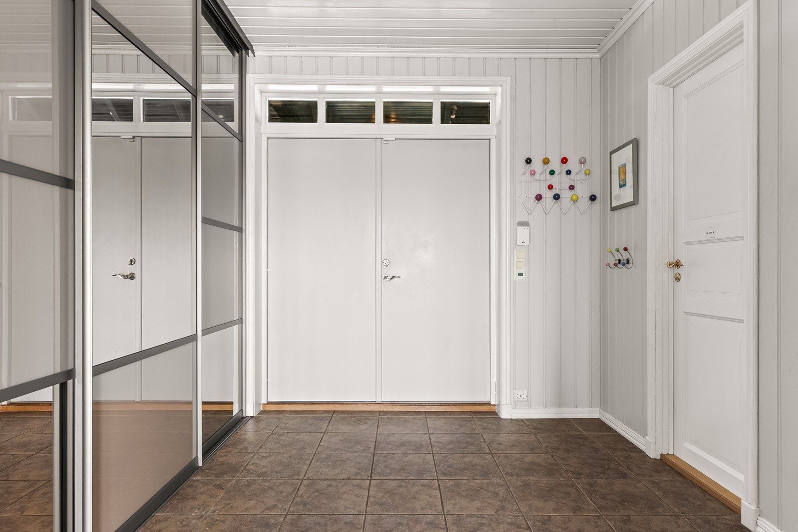 Romslig entré med flislagt gulv og god plass til oppbevaring i skyvedørsgarderobe. Galleribilde