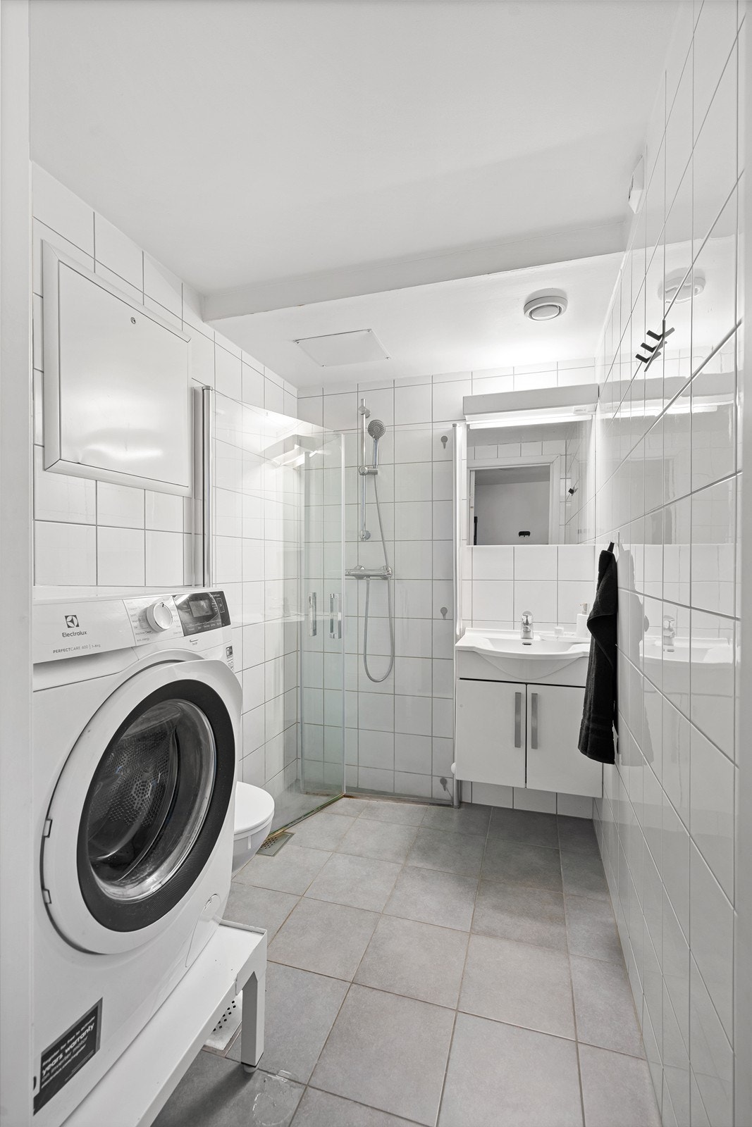 Badet er innredet med vegghengt wc, dusjnisje og vask i skapseksjon med tilhørende speil og belysning. Galleribilde