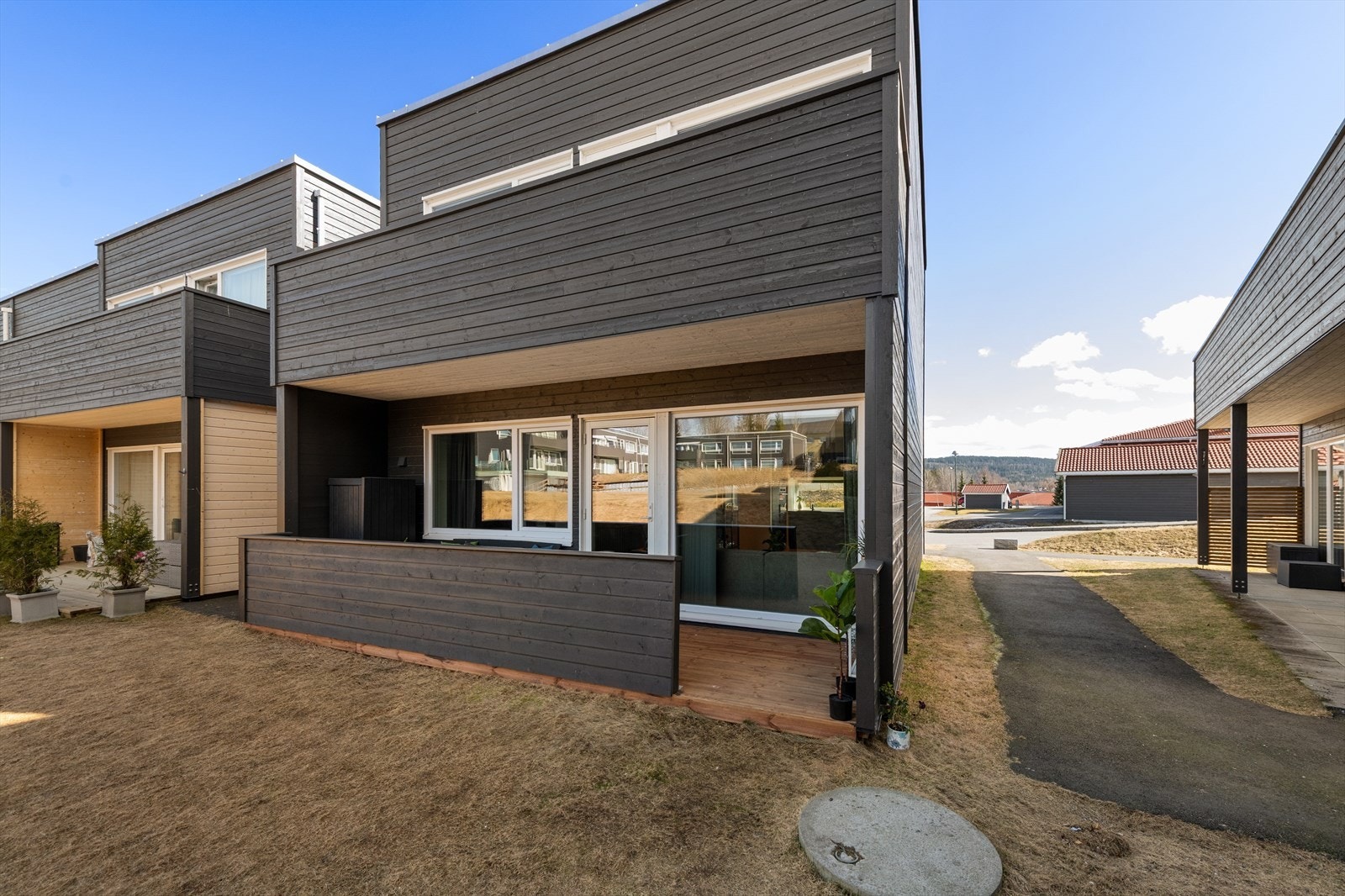 Hyggelig vestvendt og skjermet terrasse vendt mot hyggelige fellesområder. Foto tatt kl. 13 på dagen så solen har ikke rukket å komme rundt enda Galleribilde
