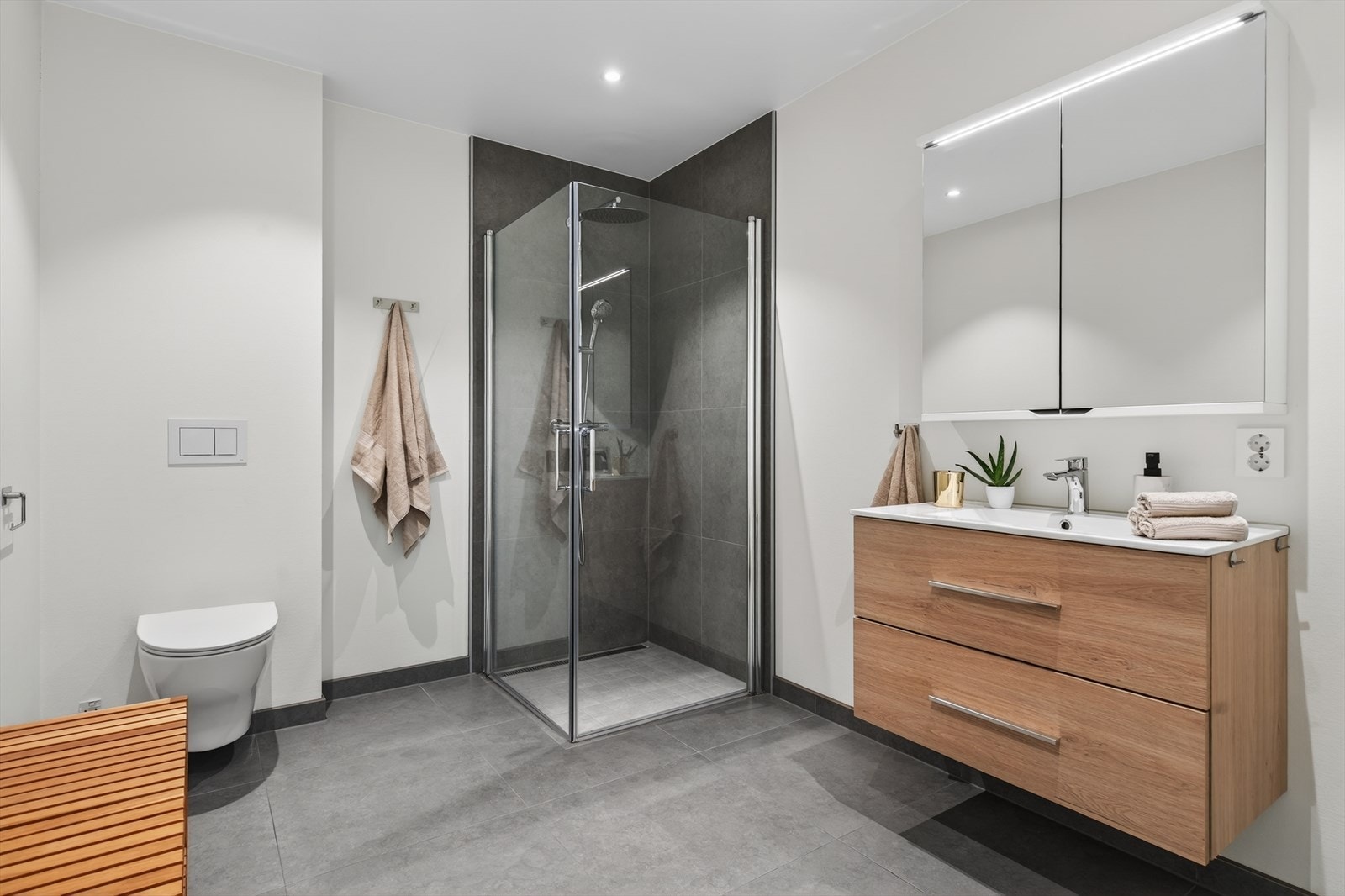 Flott baderom, innredning med heldekkende servant, veggmontert toalett og dusjvegger/hjørne. Gulvet er flislagt og det er montert vannbåren gulvvarme. Veggene har malte plater og fliser i dusjsone. Taket er malt. Galleribilde