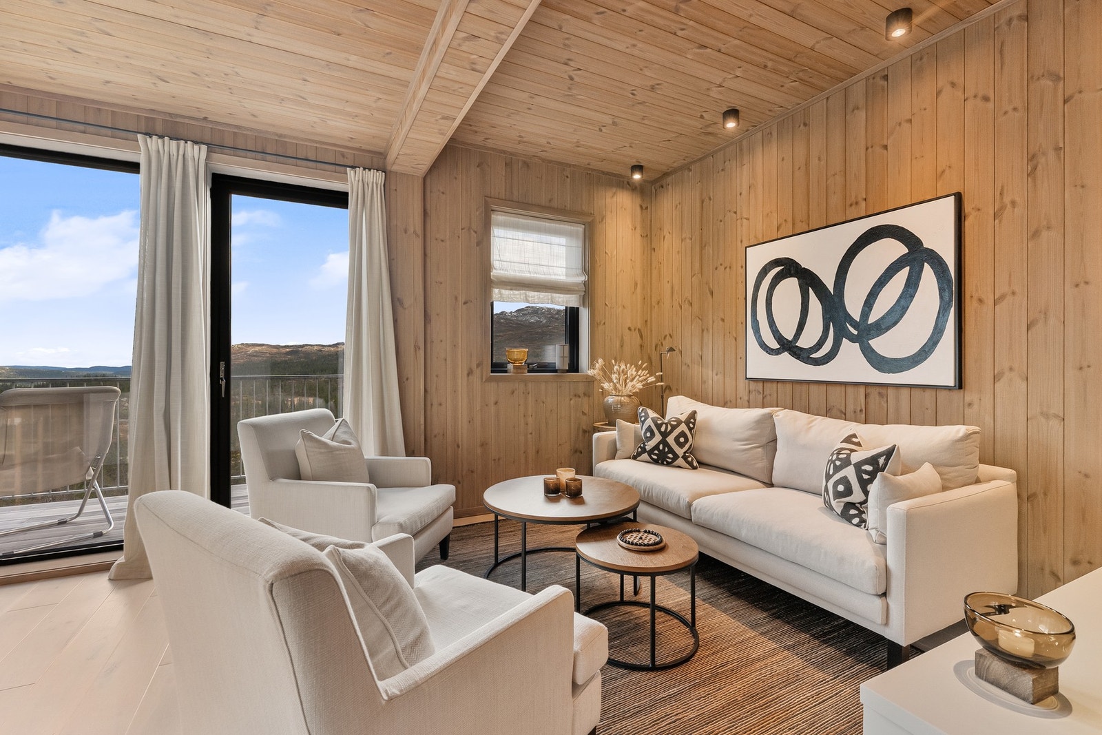 En varm og hyggelig stue hvor naturen trekkes inn gjennom store vinduer. Galleribilde
