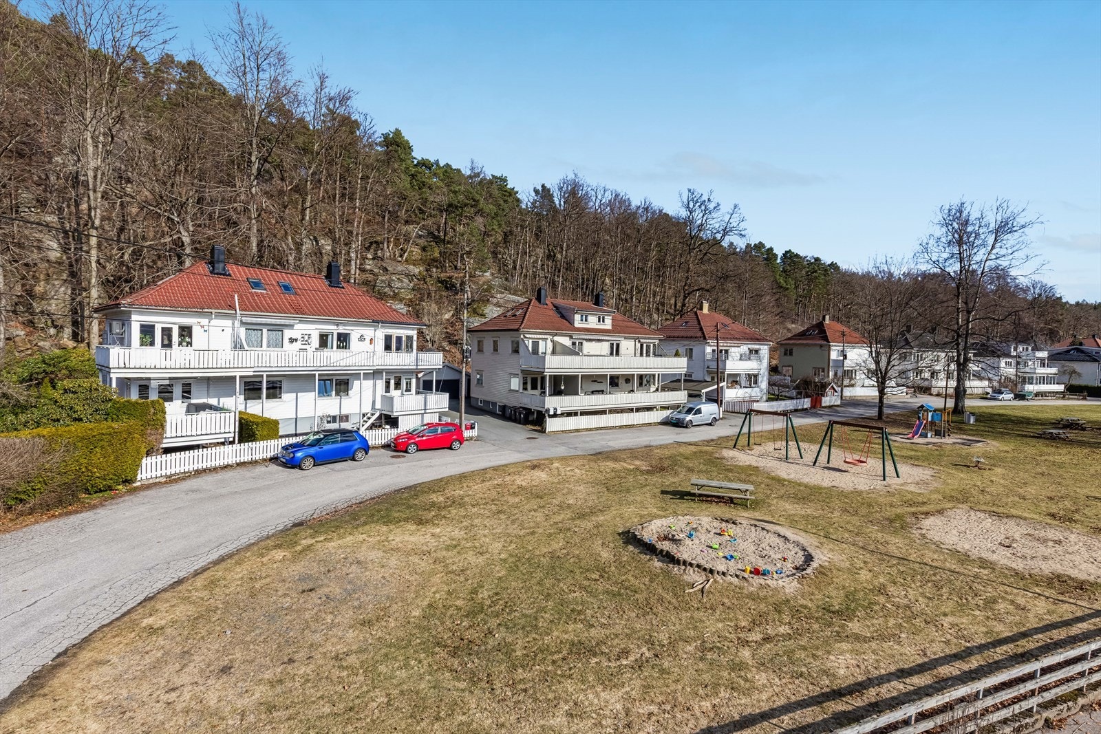 Oversiktsbilde av nærområdet med lekeplass og boligen i bakgrunnen Galleribilde