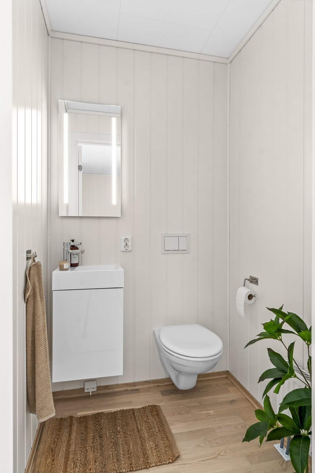 Wc-rommet fremstår som lyst og delikat, med parkettgulv og lysmalte panelvegger. Galleribilde
