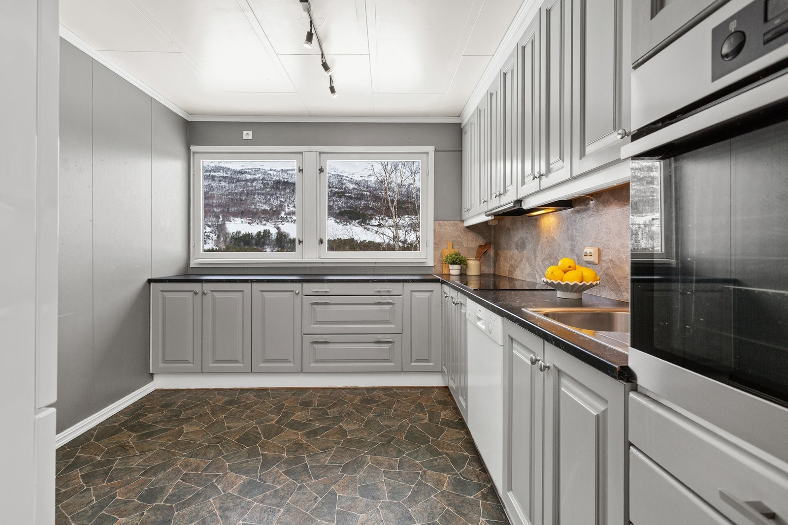 Kjøkken med lyse profilerte fronter. Kjøkkenet har integrert stekeovn og platetopp Galleribilde