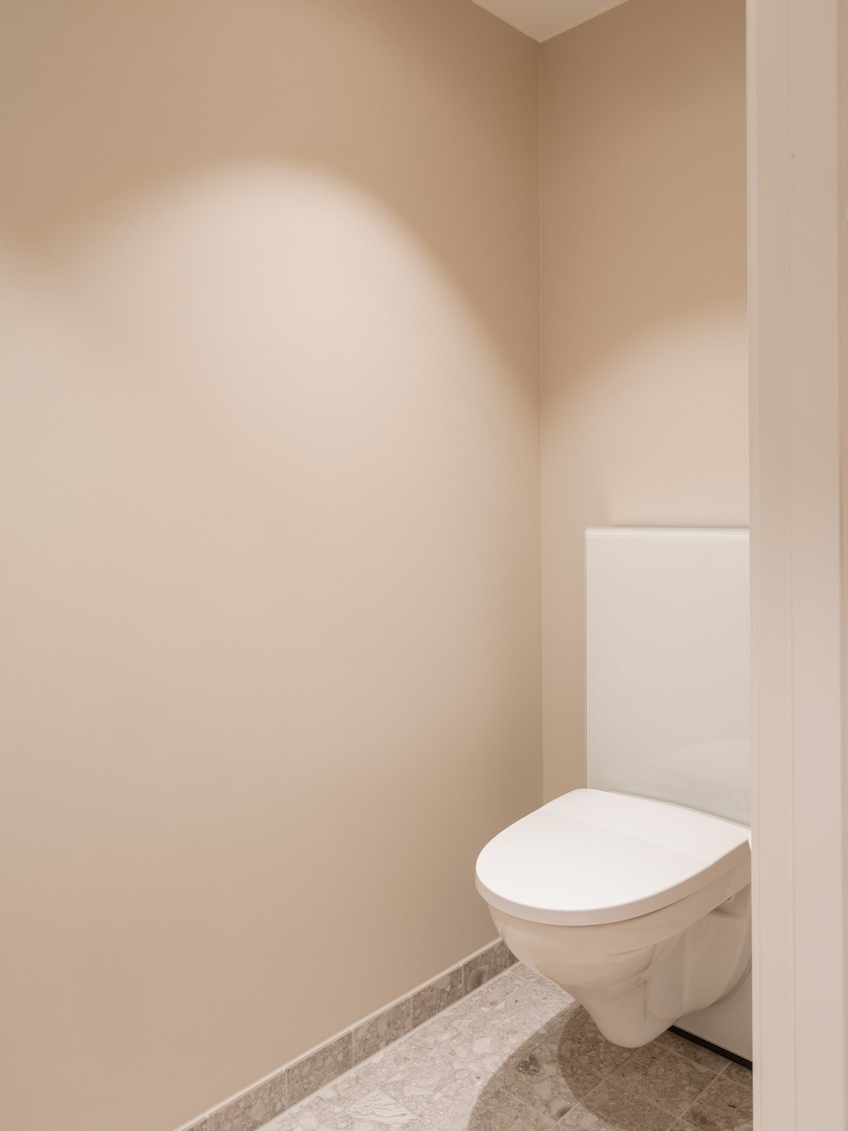 Toalettrommet er utstyrt med vegghengt toalett og fliser på gulvet. Galleribilde