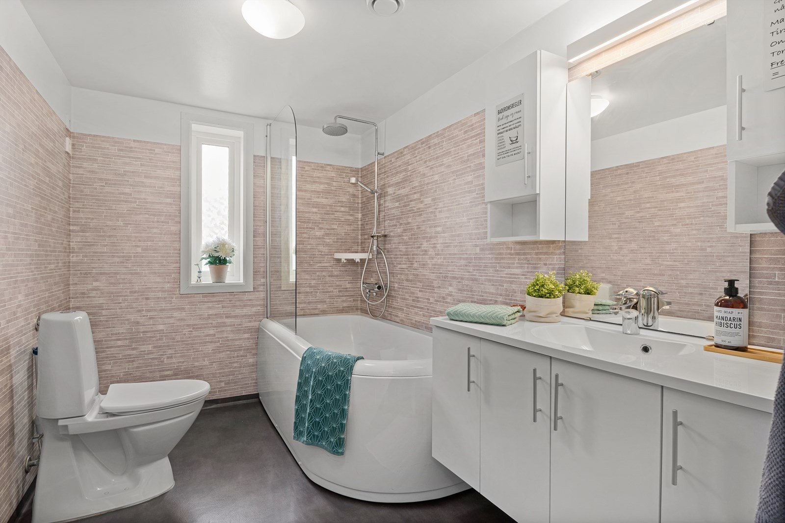 Badet har innredning med servant nedfelt i servantskap, veggskap, speil, toalett og badekar med badekarsvegg av glass og dusjgarnityr Galleribilde