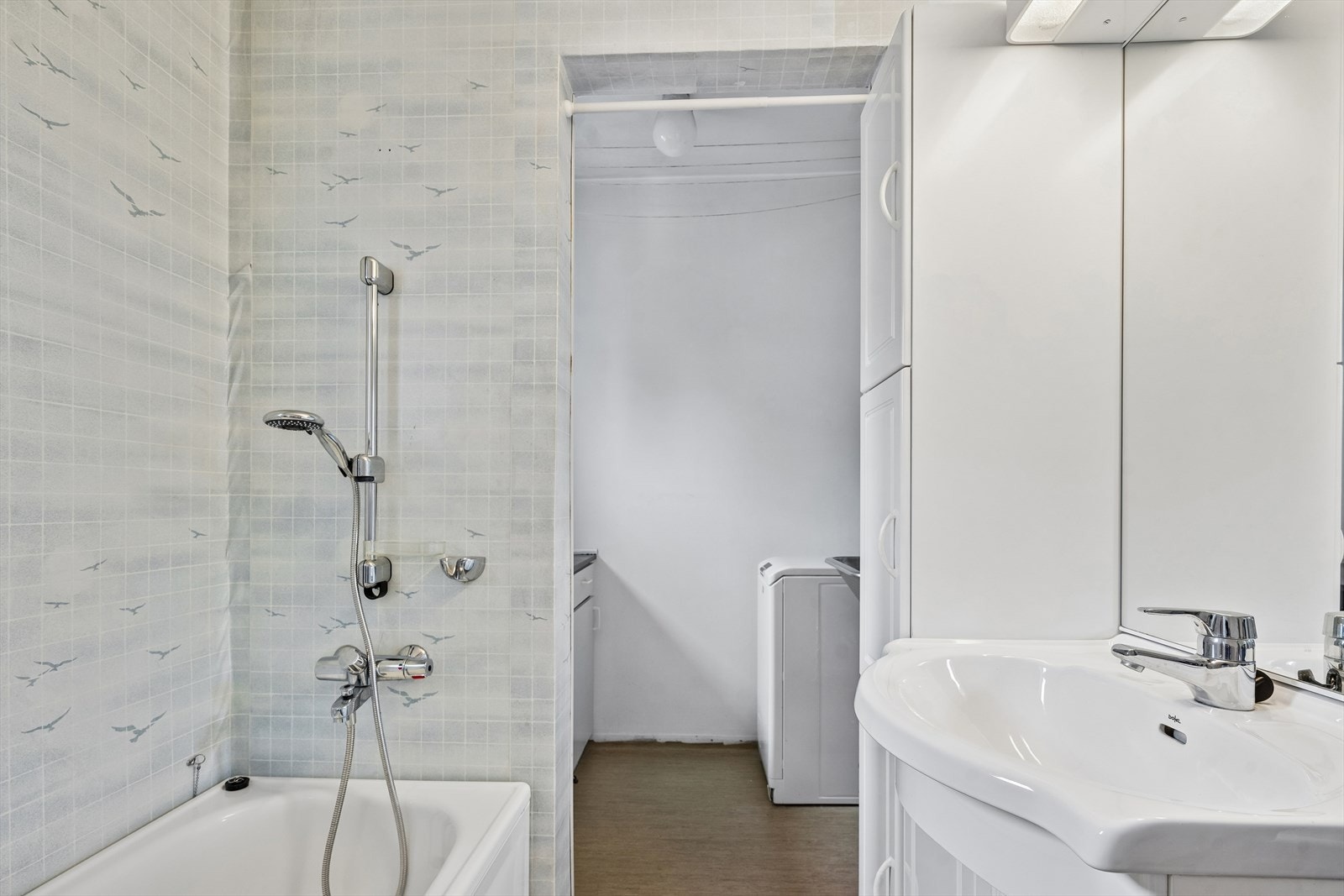 Kombinert bad og vaskerom med badekar og en egen, praktisk sone for klesvask. Galleribilde