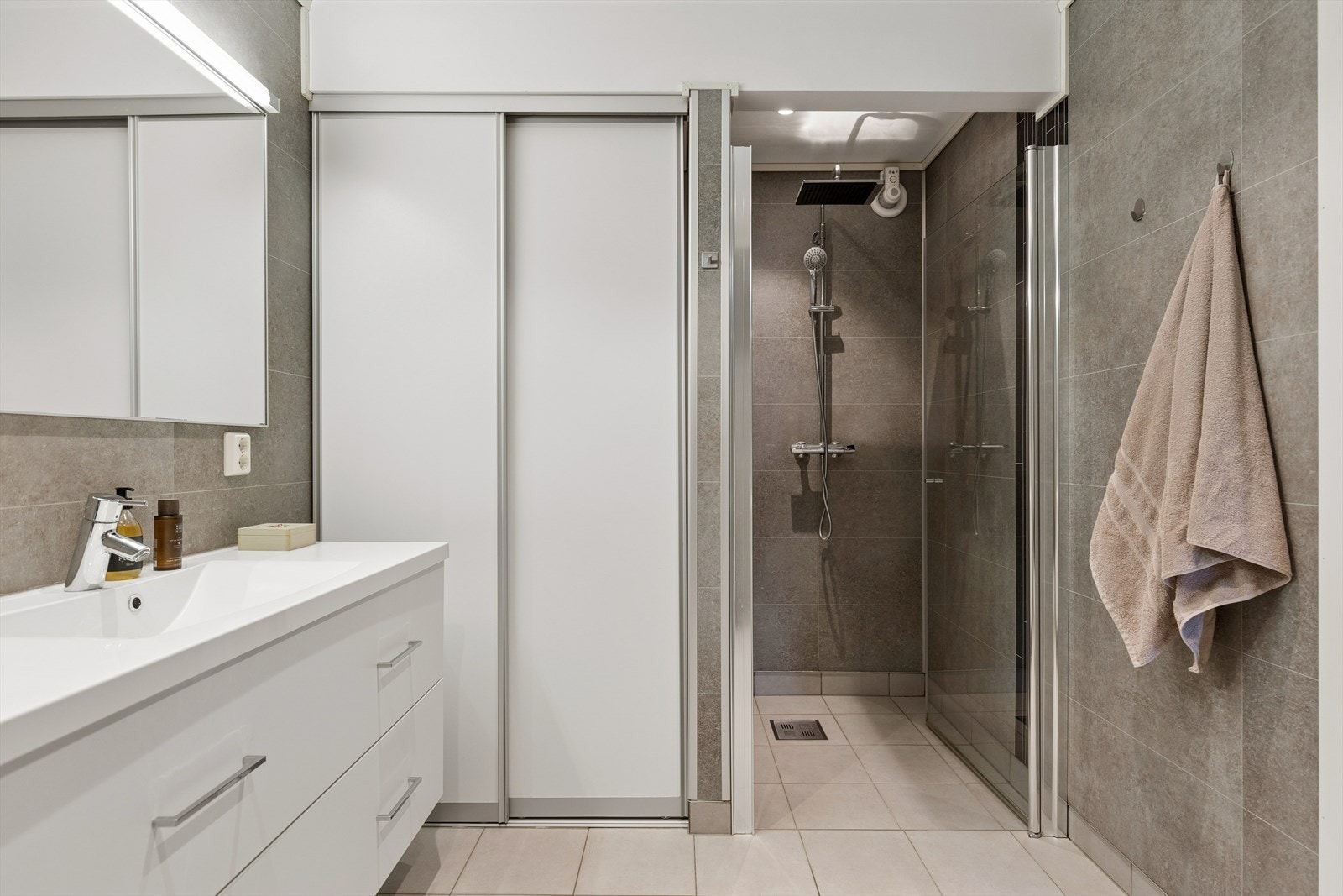 Badet har dusjnisje, seksjon med heldekkende vask, veggmontert toalett, fordelerskap for vannrør og opplegg for vaskemaskin. Galleribilde