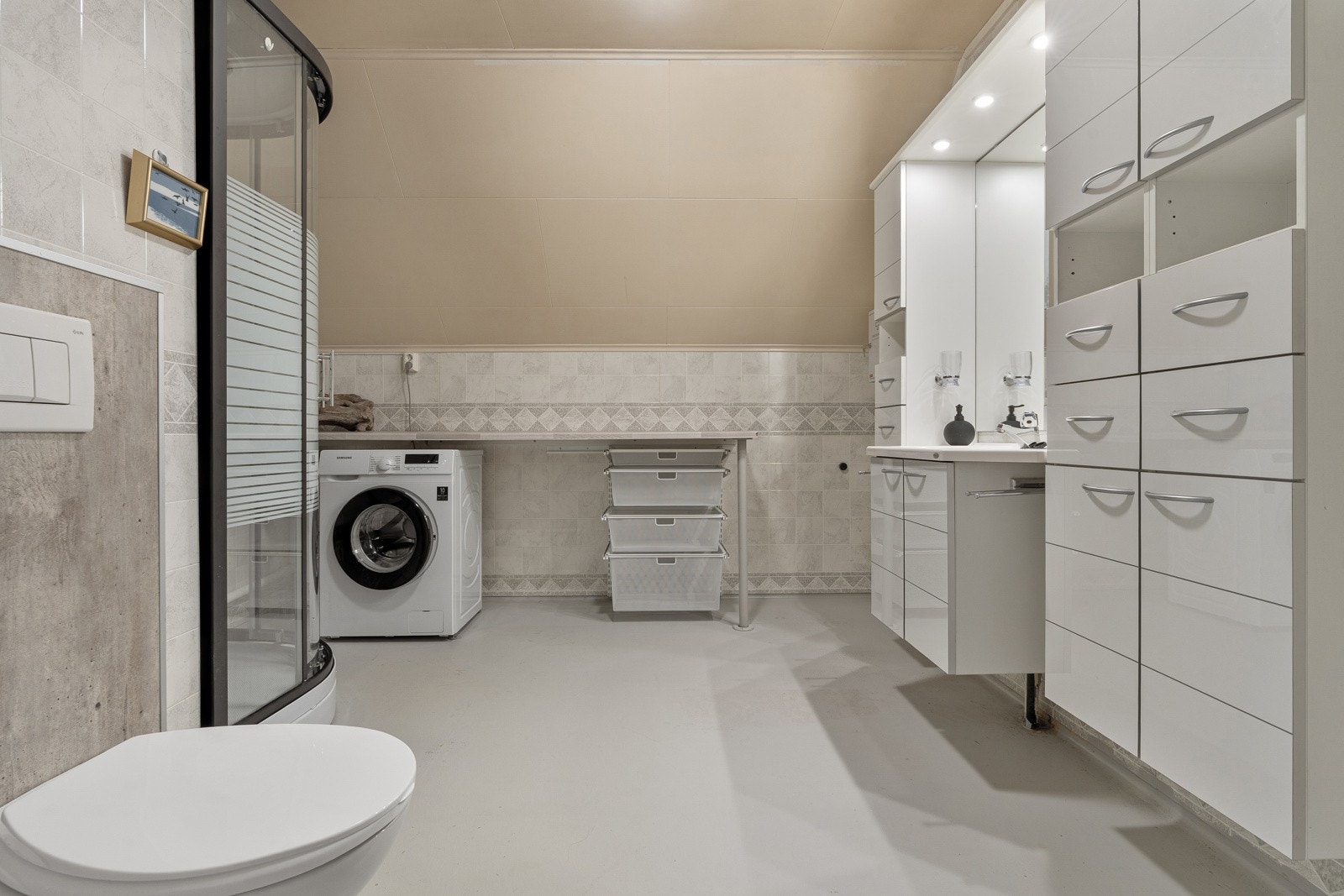 Bad/wc/vaskerom i andre plan med vegghengt wc og stor baderomsinnredning for lagring av baderomsartikler.