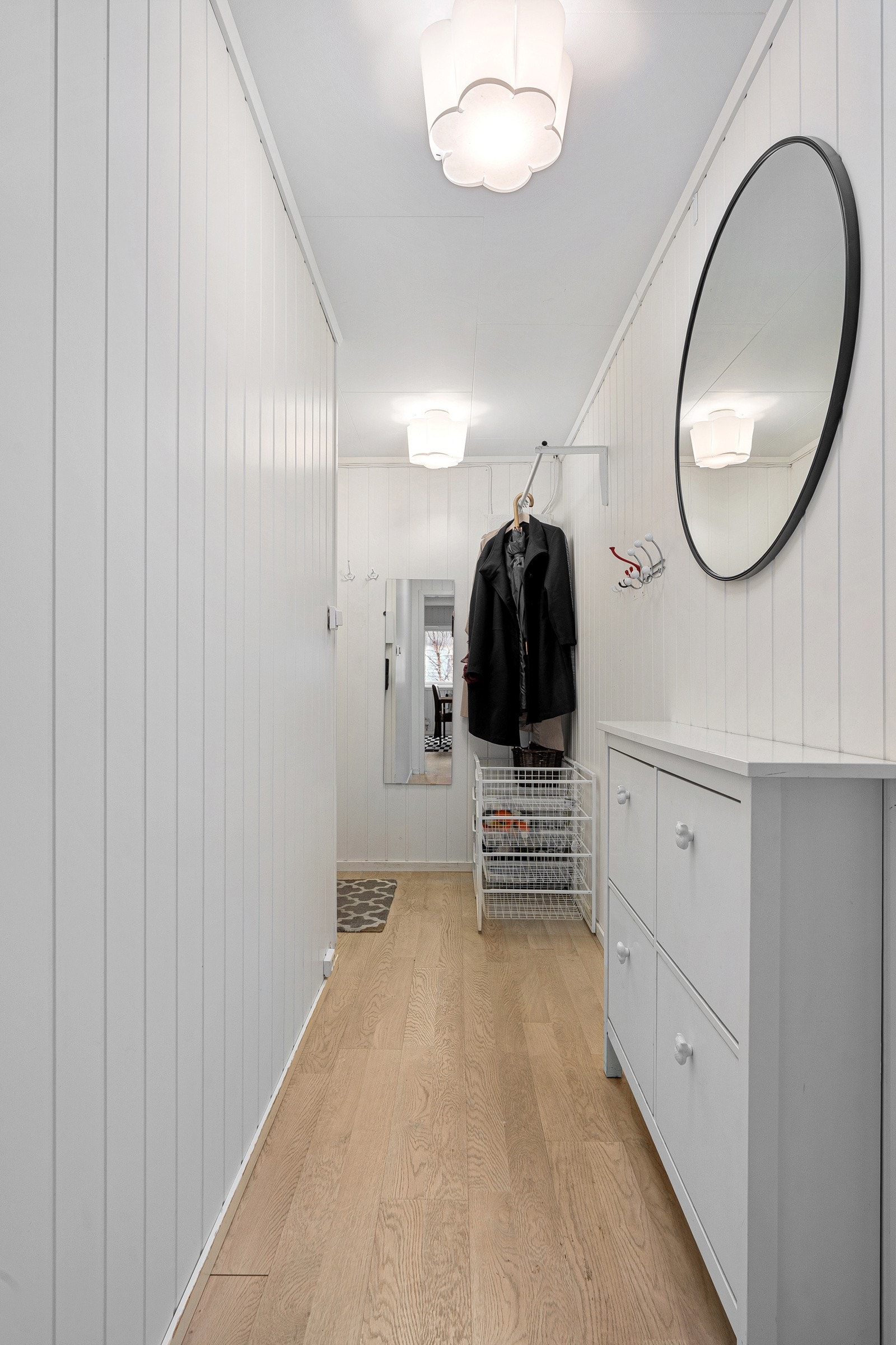 Romslig gang i første plan med plass til kommode eller skoskap. Det er adkomst til trapperom med trapp ned til kjelleren