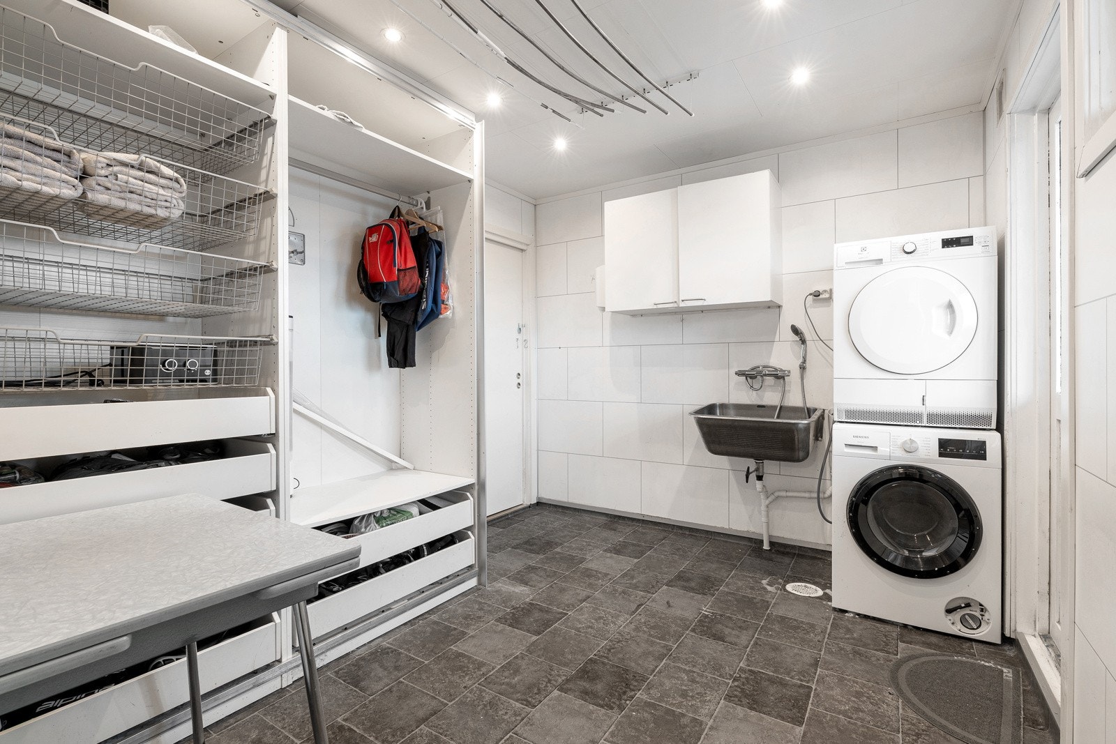 Vaskerom i første plan med god oppbevaringsplass, opplegg for vaskemaskin og utgang til balkong