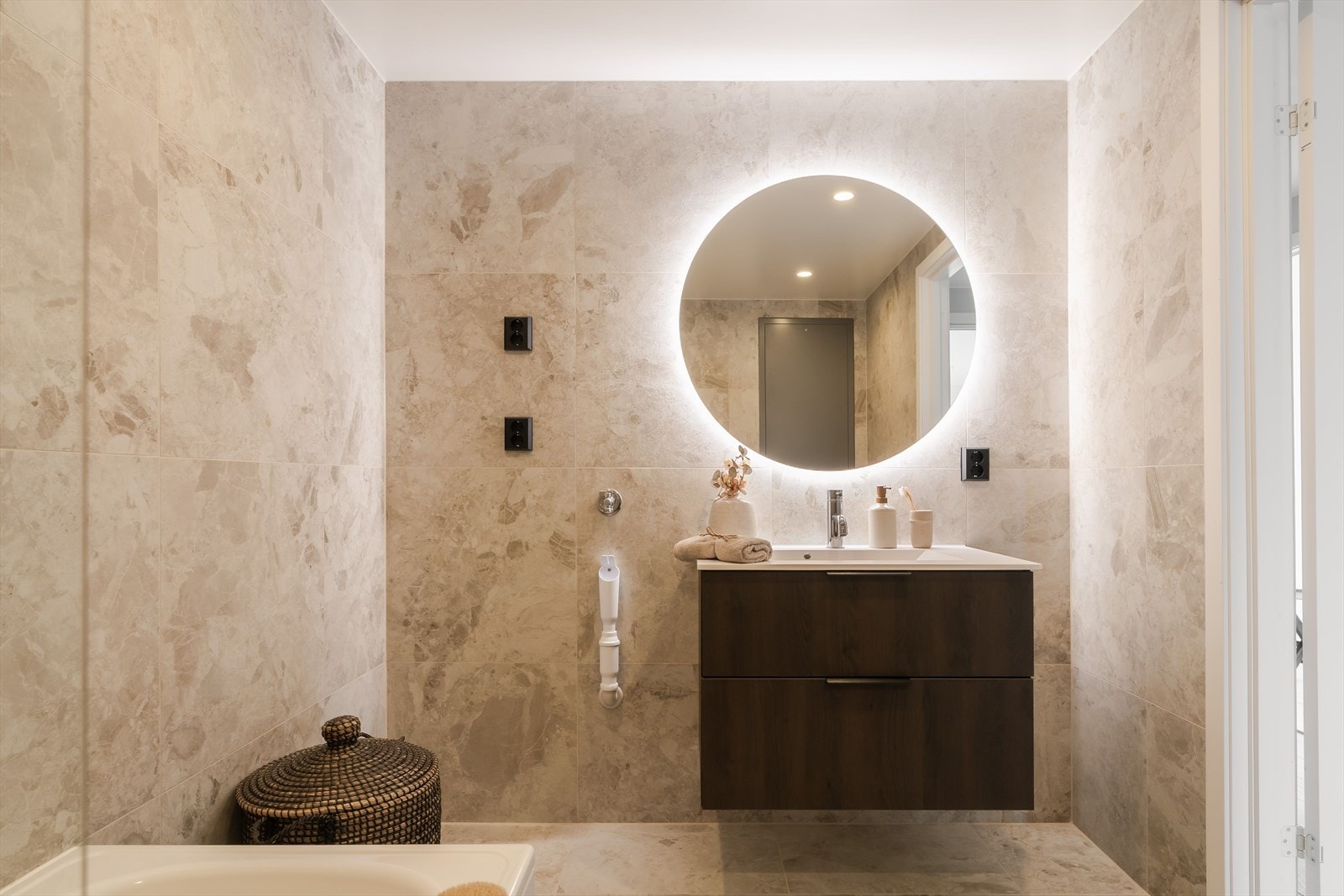 Boligen har i tillegg et ekstra bad som fremstår moderne og delikat utført med flislagte overflater i lune toner. Badet er innredet med badekar med dusjløsning, vegghengt toalett og servant med underskap som gir gode oppbevaringsmuligheter. Galleribilde