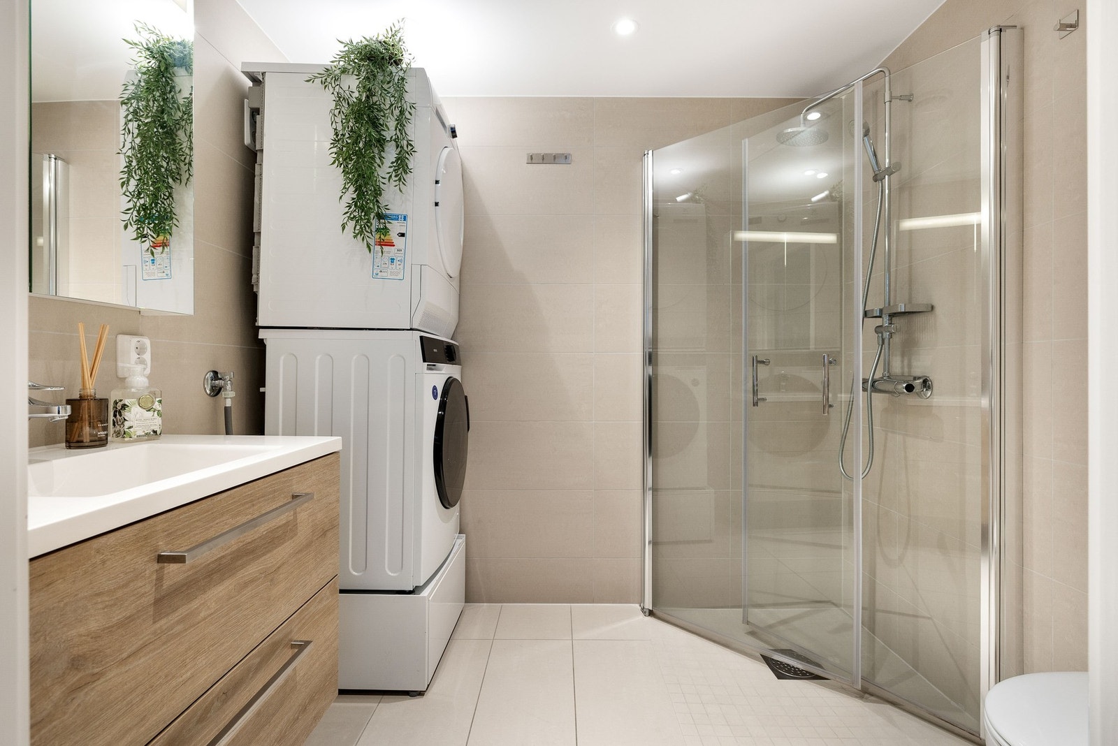 Badet er elegant innredet med servant, toalett, dusjhjørne og opplegg for vaskemaskin, og kombinerer stil og funksjonalitet på en gjennomført måte. Galleribilde