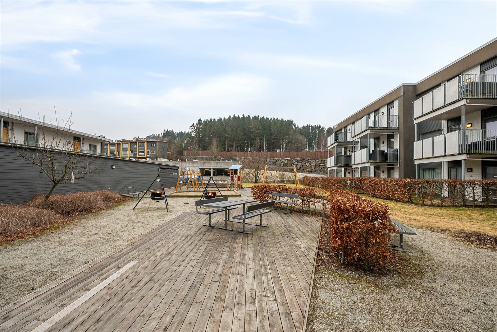 Fellesområdet i midten av tomten med sittegrupper, lekeplass og utvendige boder. Galleribilde