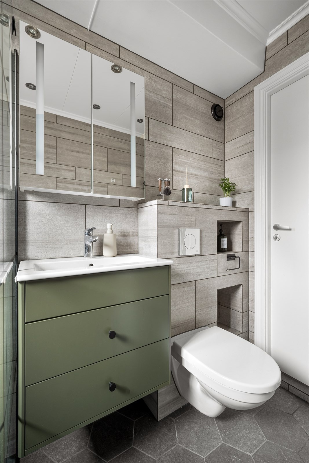 Baderomsinnredningen har godt med oppbevaring i skuffer, supplert av et praktisk speilskap med belysning. Galleribilde