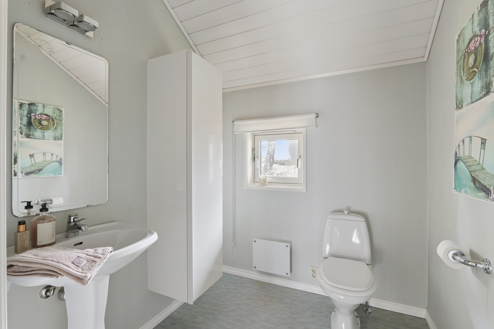 Toalettrommet har belegg på gulv og tapet på vegger, samt innredning med skap. Galleribilde