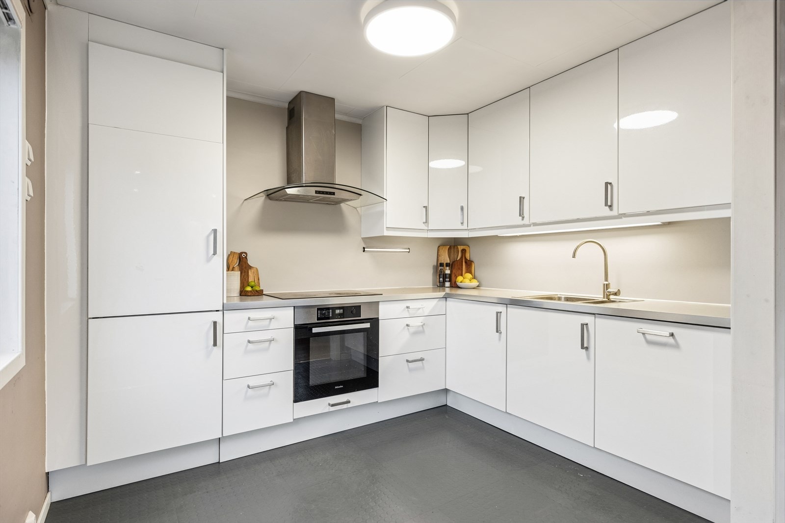 Det har glatte fronter, integrerte hvitevarer og ventilator med avtrekk ut. Det er montert lekkasjesikring på kjøkkenet. Galleribilde