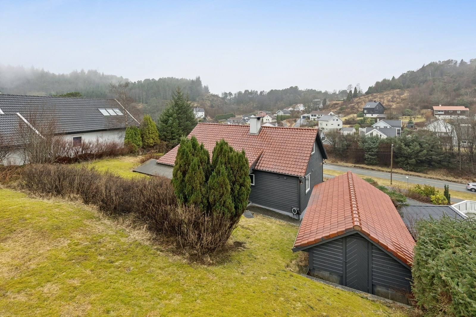Opparbeidet tomt med asfaltert gårdsrom, enkel garasje med bod og stor dobbelgarasje. Galleribilde