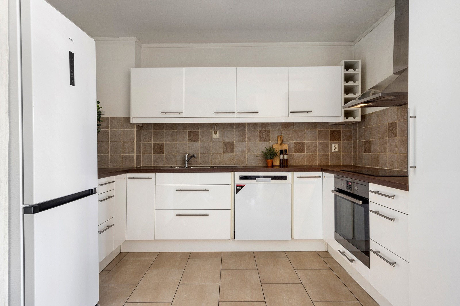 Kjøkken med glatte høyglansede fronter og godt med benkeplass. Integrert komfyr og platetopp Galleribilde