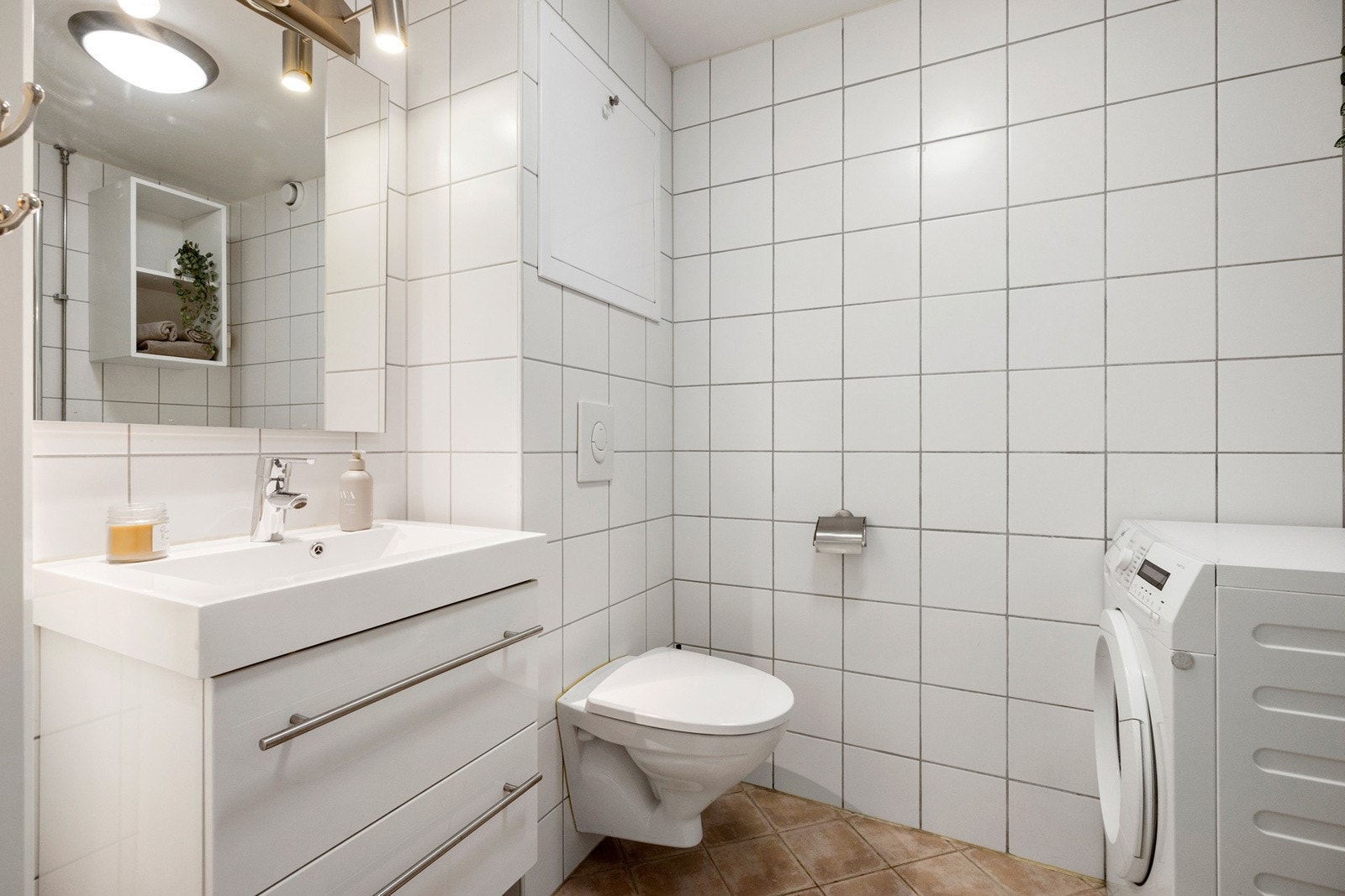 Servantinnredning m/skuffer, speil m/lys, veggskap, veggmontert toalett og dusjhjørne, samt opplegg for vaskemaskin Galleribilde