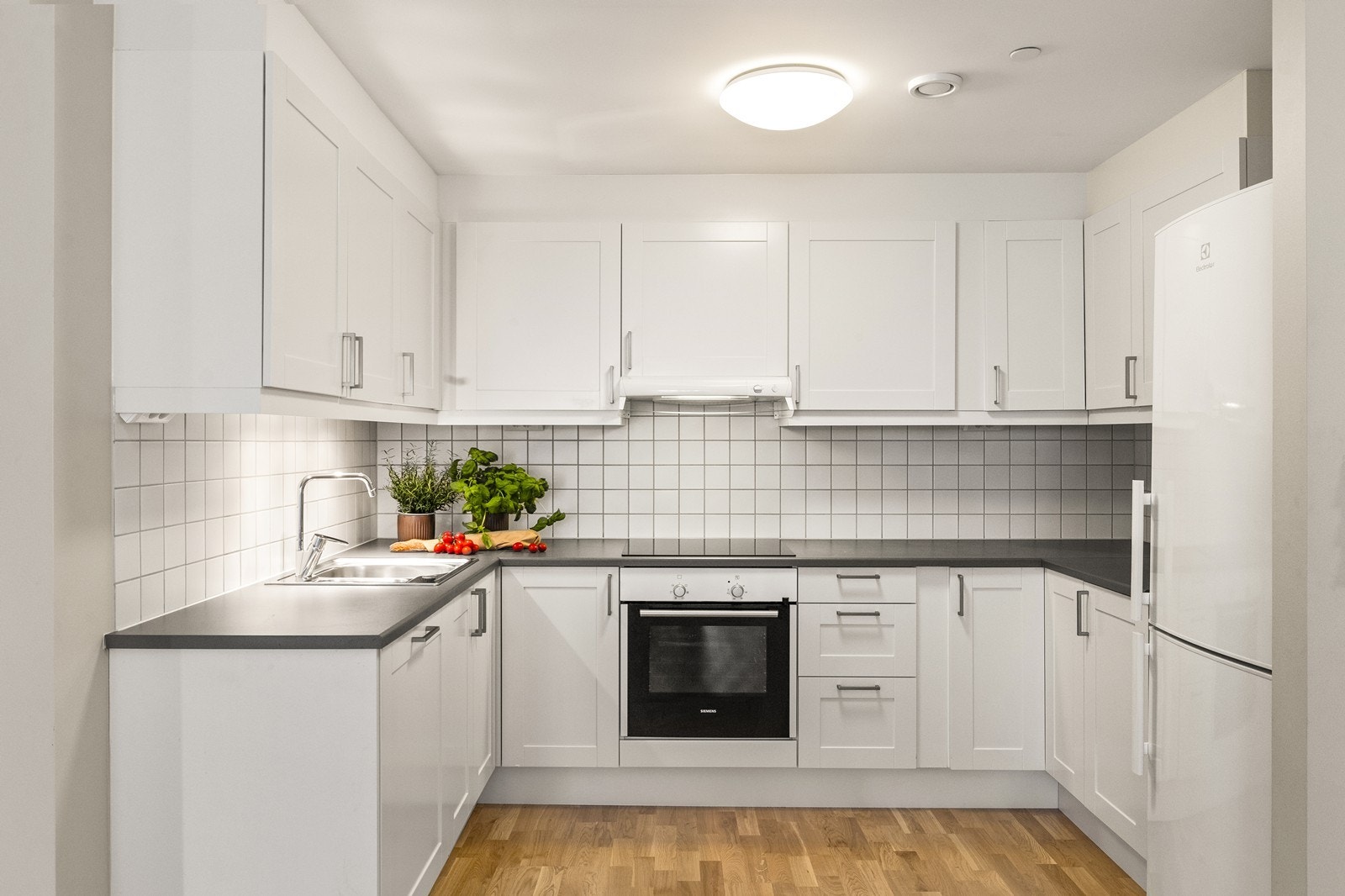 Stilrent kjøkken med profilerte fronter og slitesterk laminatbenkeplate. Innredningen inkluderer integrert stekeovn, induksjonstopp og oppvaskmaskin. Galleribilde