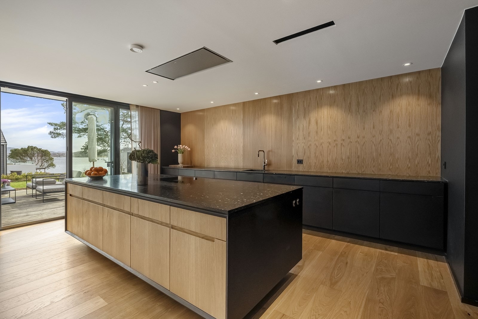 Kjøkken i åpen og stilren form. Ingen overskap for å skape en ryddig og åpen løsning. Galleribilde