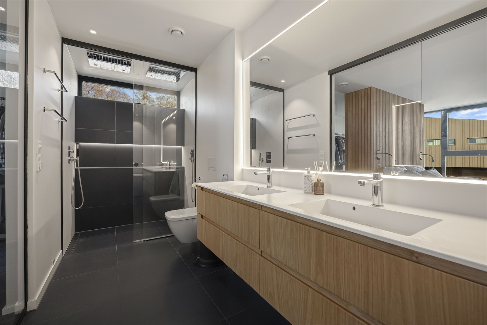 Dobbeldusj innfelt i taket, håndklevarmer, hylle for produkter. Det hele toppet med et lekkert overlys som slipper tretoppene inn på badet. Galleribilde