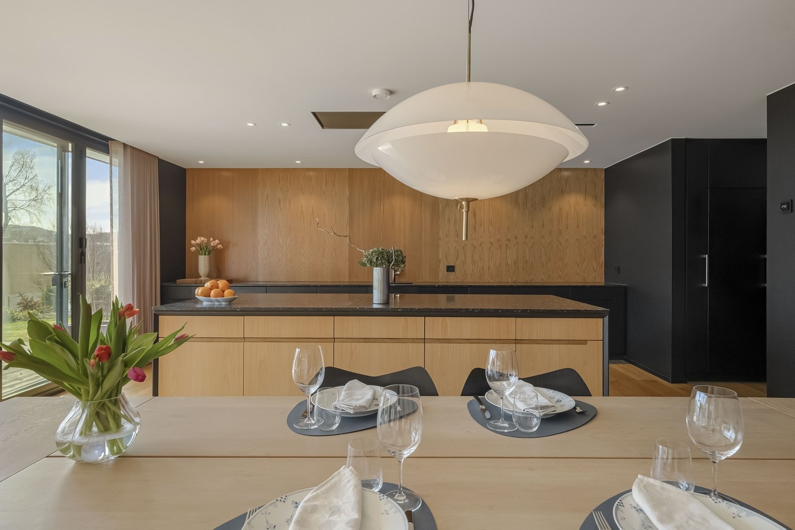 Detlajer teller. Gardinene ligger skjult i overkant av terrassedør. Lyssetting med spotter i par adskilt gir riktig belysning av kjøkkenet Galleribilde