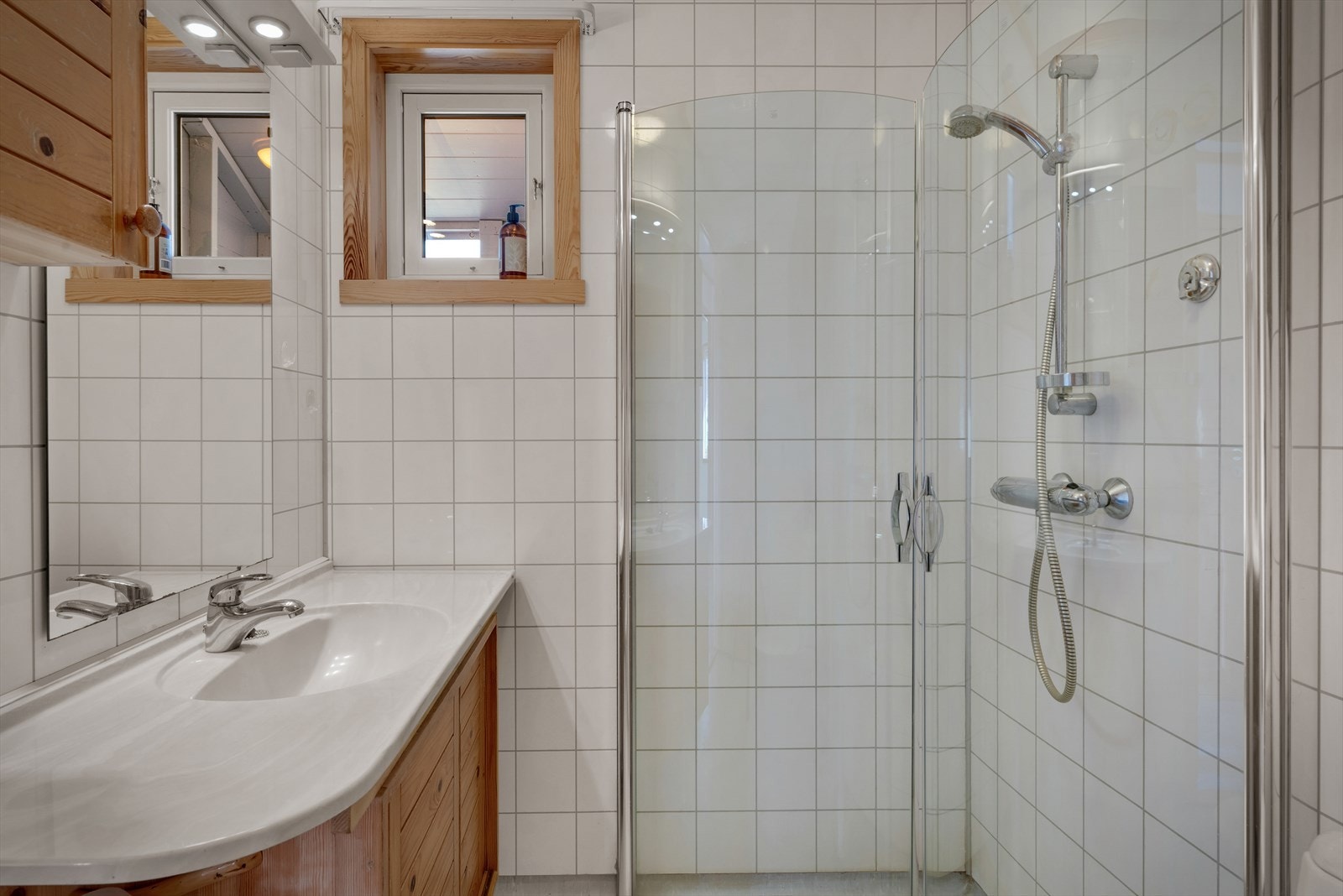 Badet er innredet med nedfelt servant, toalett, dusjhjørne med innfellbare glassvegger og opplegg for vaskemaskin. Galleribilde