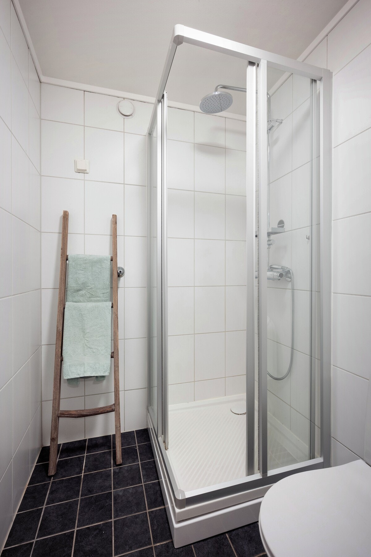 Badet er innredet med baderomsmøbel med servant, speil med belysning, dusjhjørne med glassdører og toalett. Galleribilde