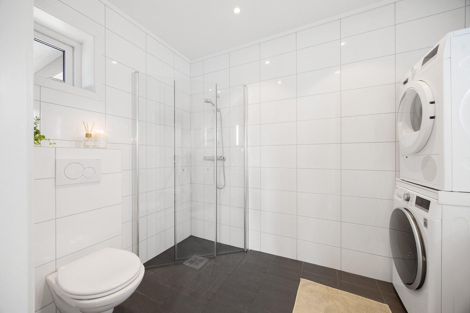 Badet er innredet med dusjhjørne med glassdører, vegghengt toalett og servantinnredning med skap og speil med lys. Rommet har balansert ventilasjon. Galleribilde