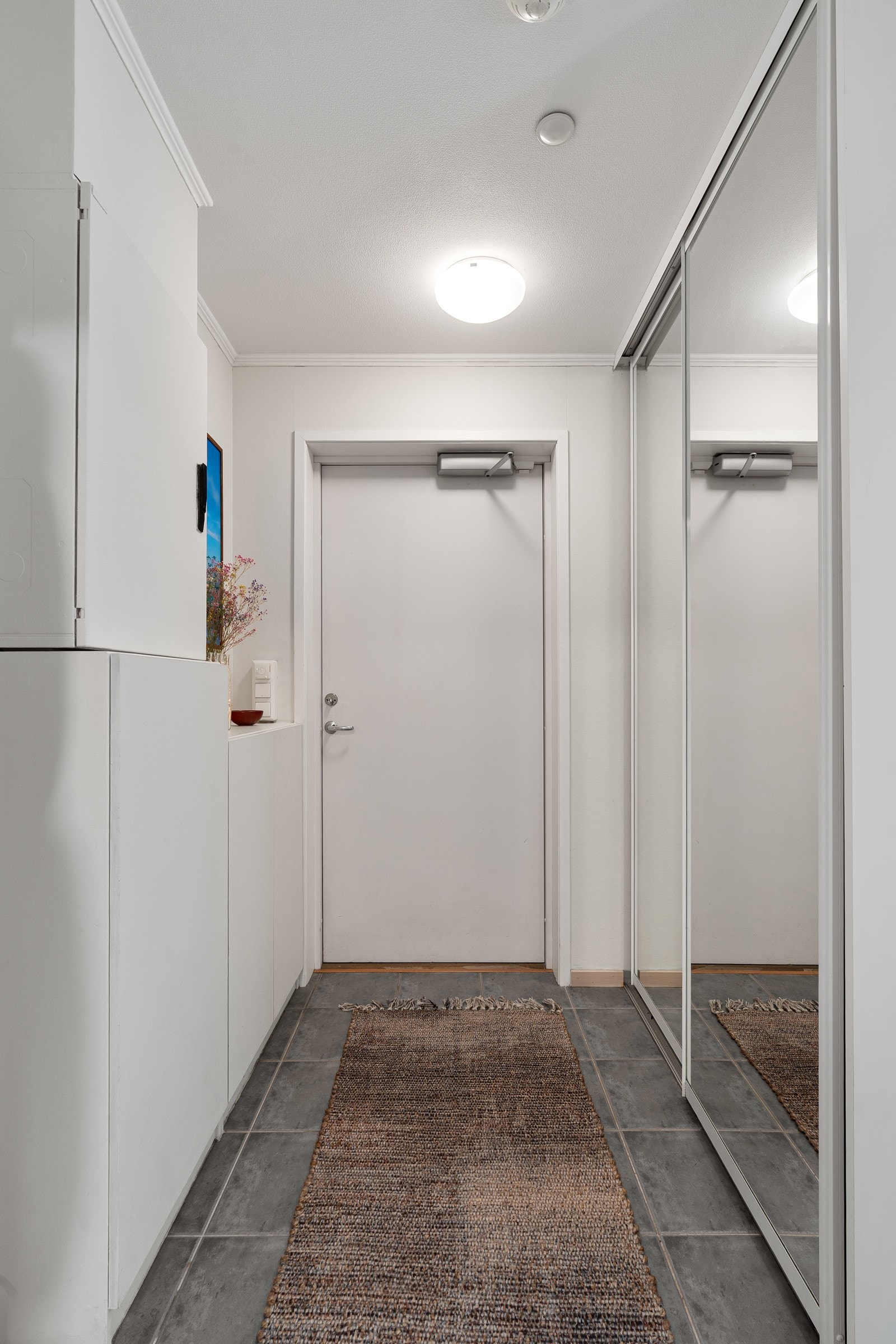 Romslig inngangsparti med skyvedørsgarderobe med speilfronter. Galleribilde