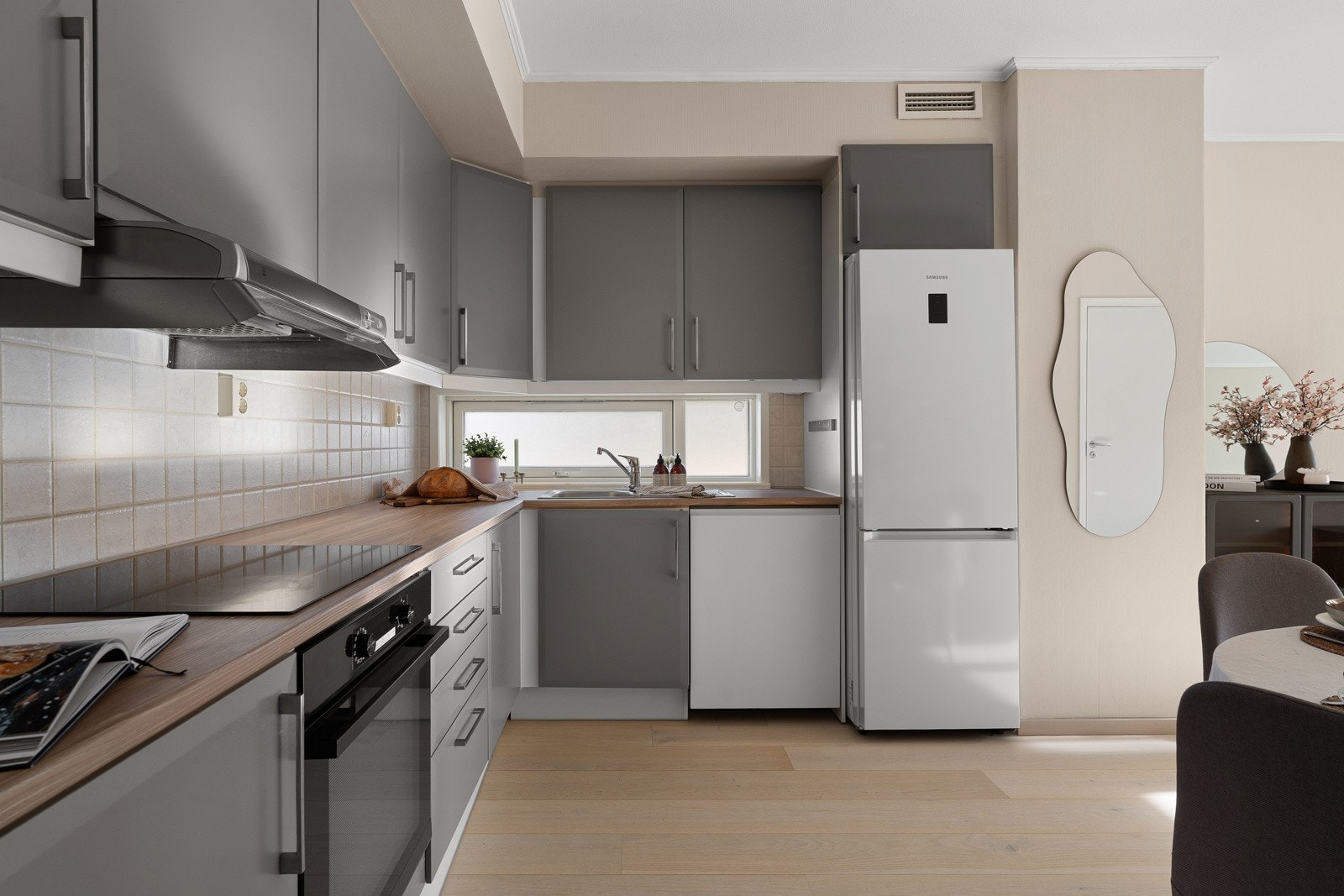 Stilrent kjøkken med mye skapplass og vindu over benk. Galleribilde