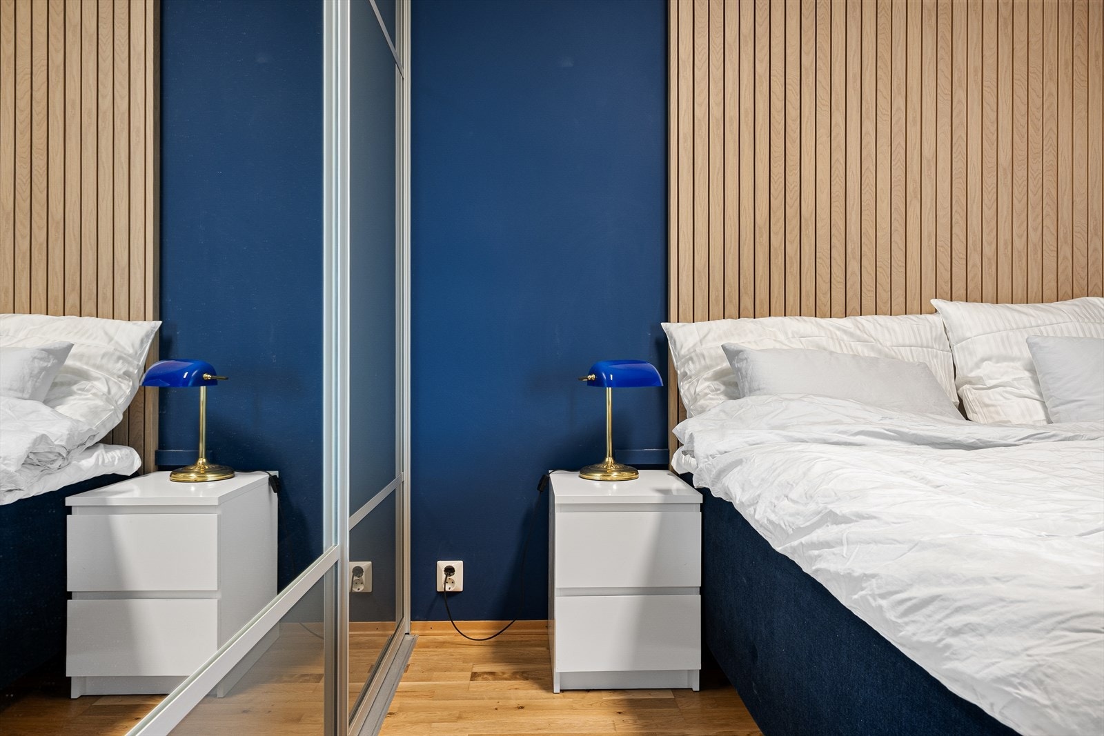 Hovedsoverommet har en lun, mørk blå fargetone og dekorative spiler bak sengen. Galleribilde