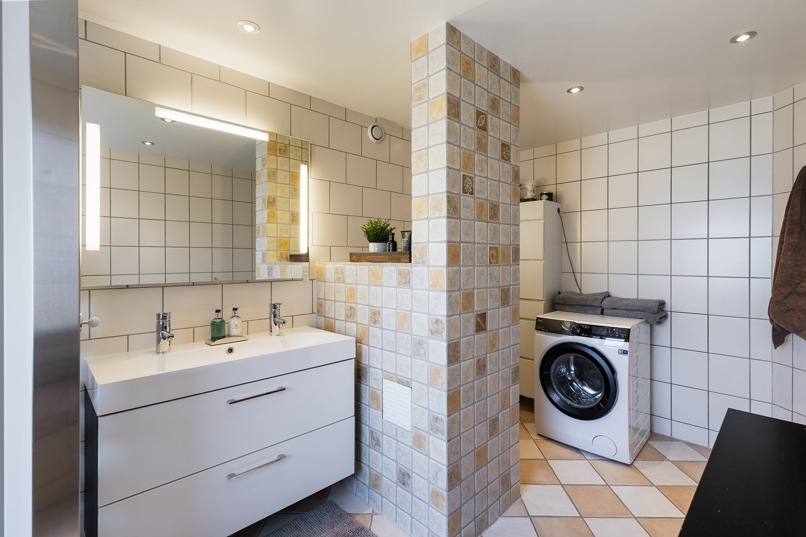 Badet er utstyrt med dobbel servant med skuffer, vegghengt toalett og opplegg for vaskemaskin. Galleribilde