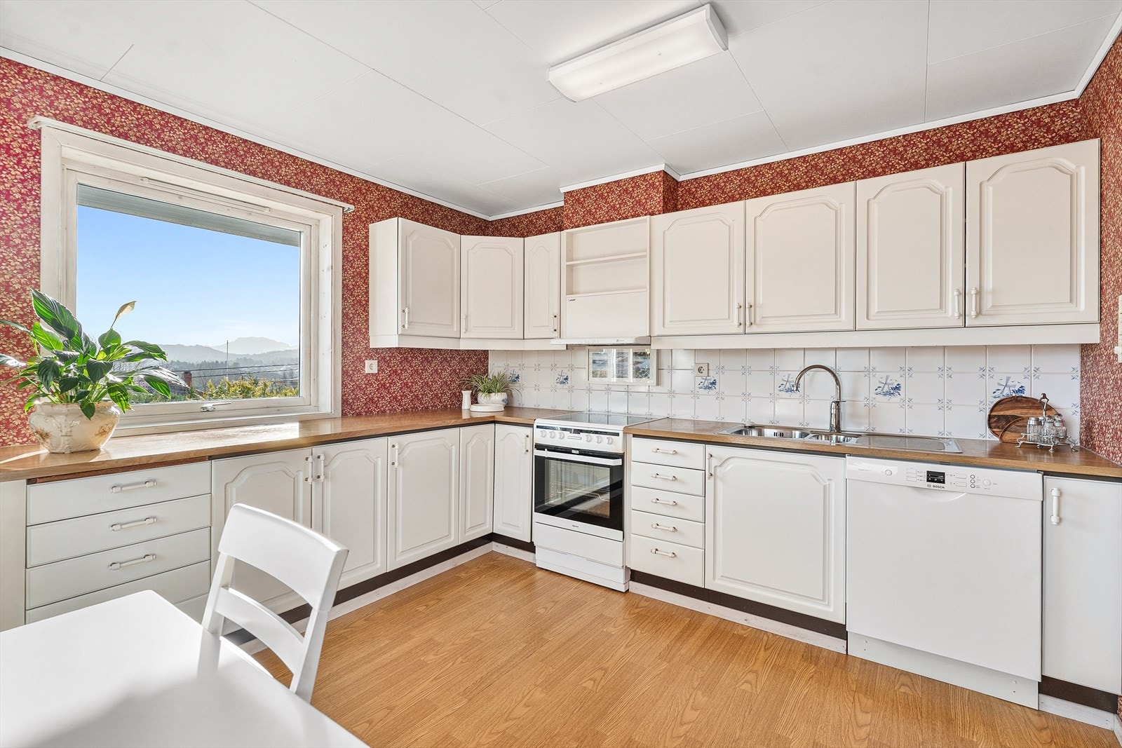 Kjøkkenet har innredning med profilerte plater og benkeplate av laminat Galleribilde