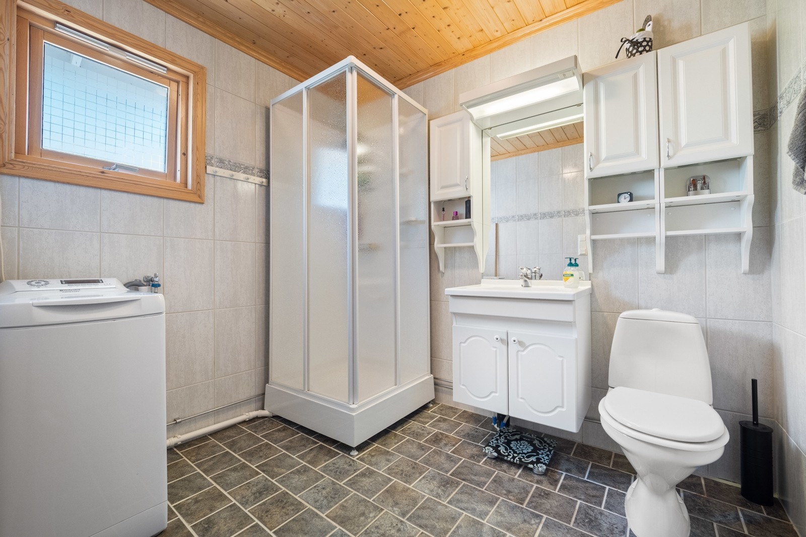 Badet har flislagt gulv med varme. Panelbord i himling. Galleribilde