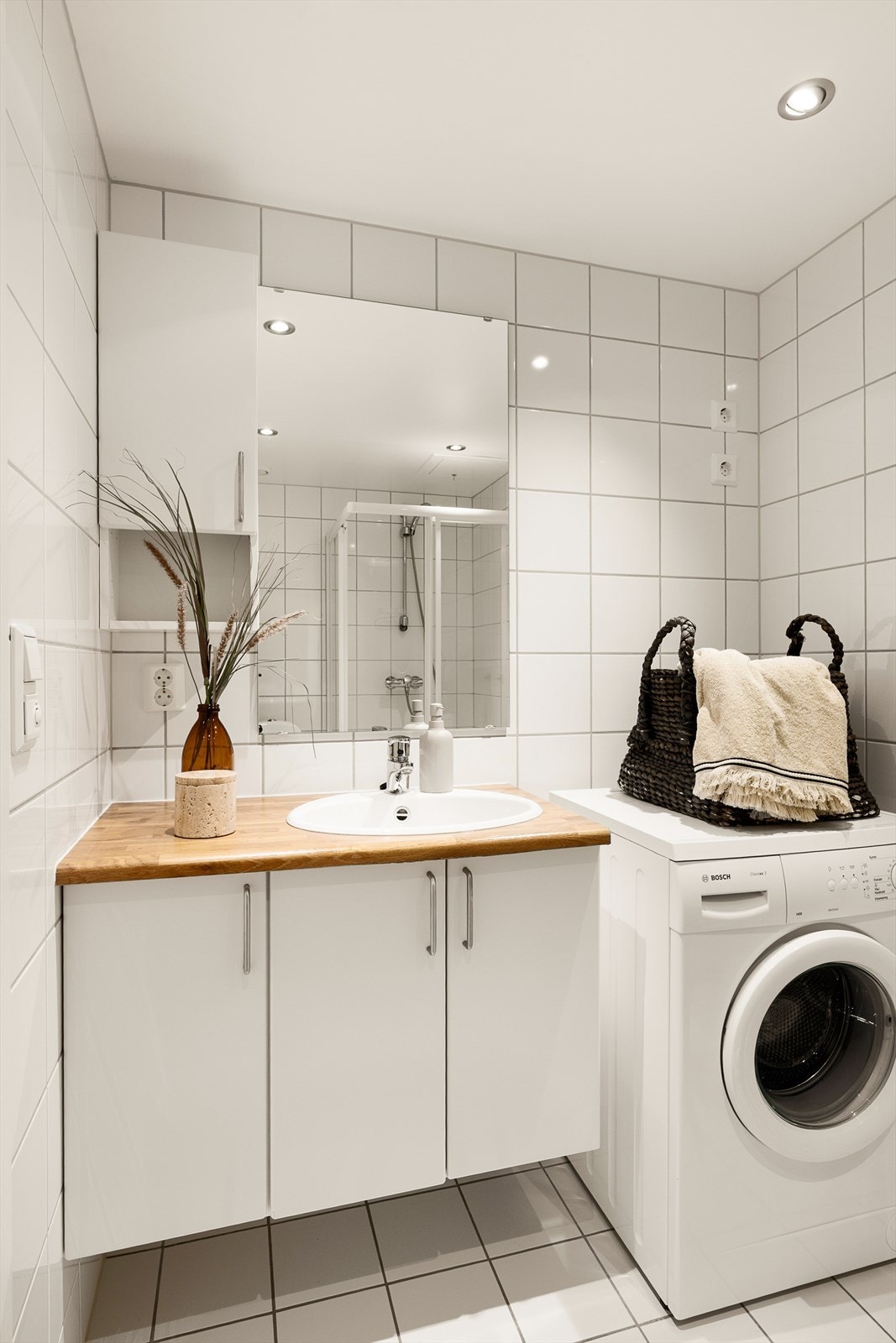 Badet er utstyrt med servantinnredning, vegghengt toalett, dusjhjørne og opplegg for vaskemaskin. Galleribilde
