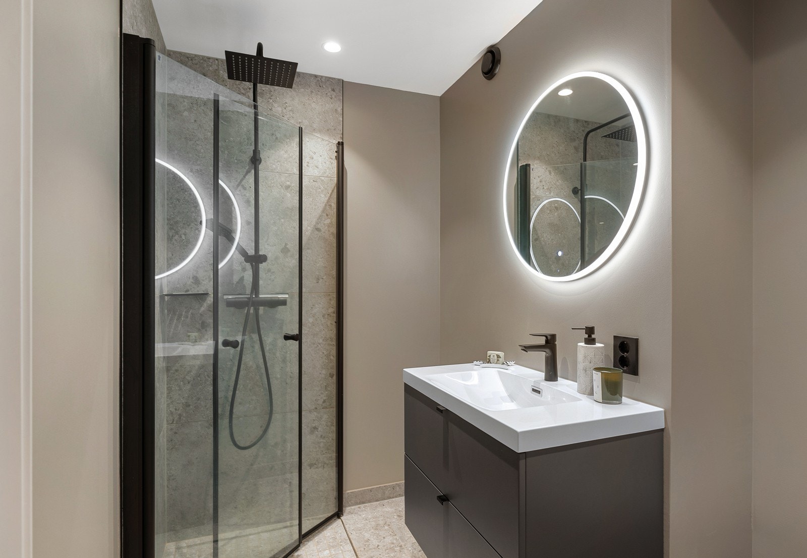 Det er flislagte gulv med varme, baderomsmaling på vegger og tak, samt downlights i himling. Badet har også opplegg for vaskemaskin. Galleribilde