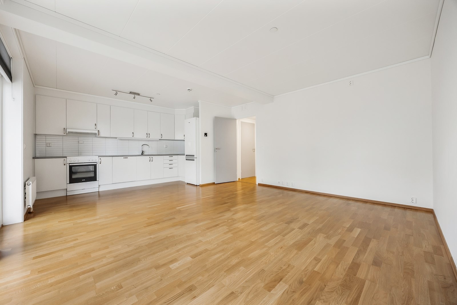 Den åpne løsningen mellom stue og kjøkken skaper en sosial og luftig sone med gjennomgående eikeparkett. Galleribilde