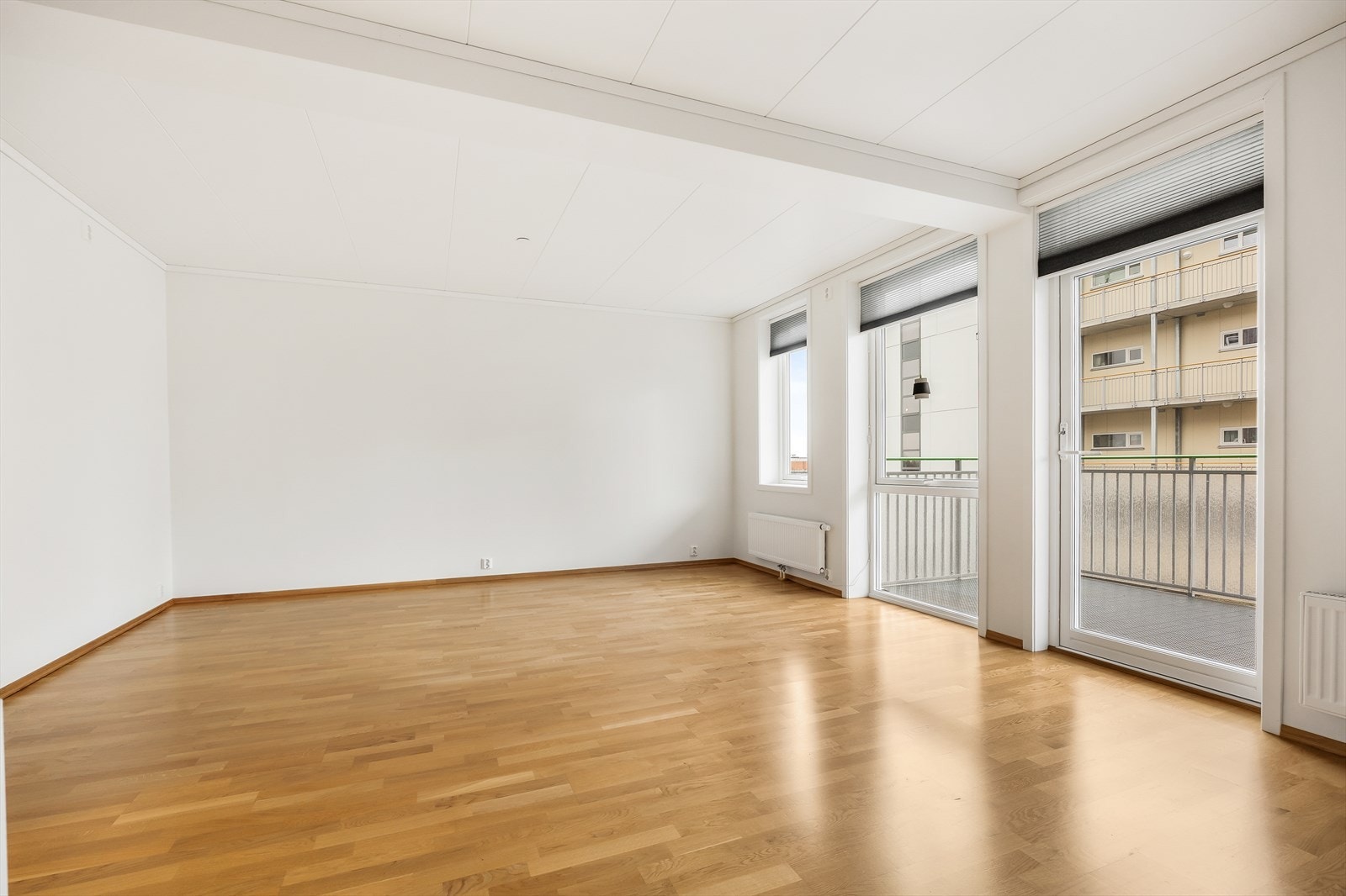 Store vindusflater og dør mot balkongen gir rikelig med dagslys inn i oppholdsrommet. Galleribilde