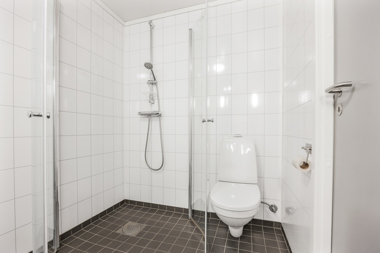 Her er det dusjhjørne med glassdører, vegghengt toalett og opplegg for vaskemaskin. Galleribilde