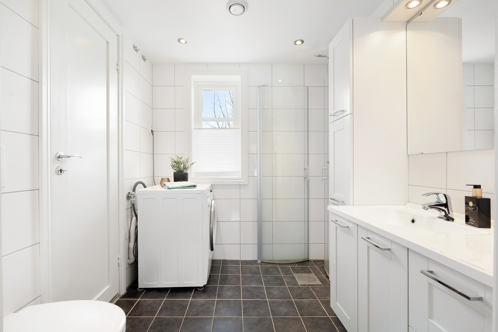 Flott flislagt baderom med gulvvarme, opplegg for vaskemaskin og downlights i tak. Galleribilde