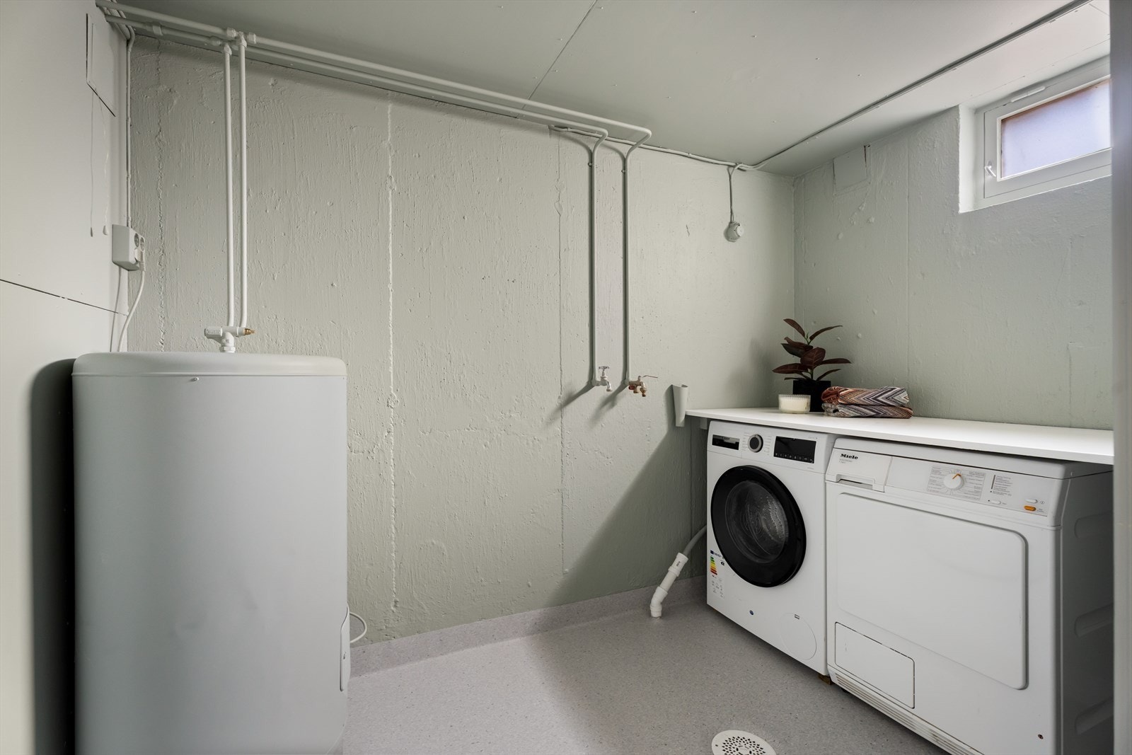 Praktisk vaskerom med nylig oppussede overflater, opplegg for vaskemaskin og en 200-liters varmtvannsbereder. Galleribilde