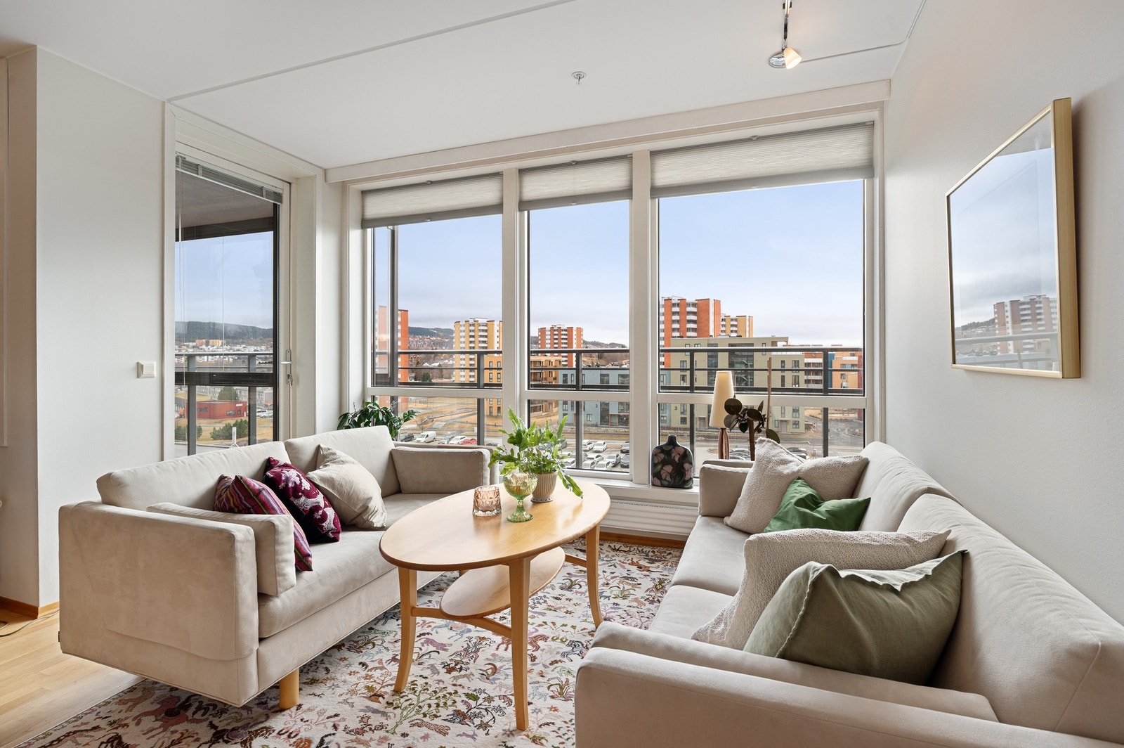 Luftig og lys romfølelse i leiligheten. Det er montert måltilpassede plisségardiner på flere av vinduene i stua. Galleribilde