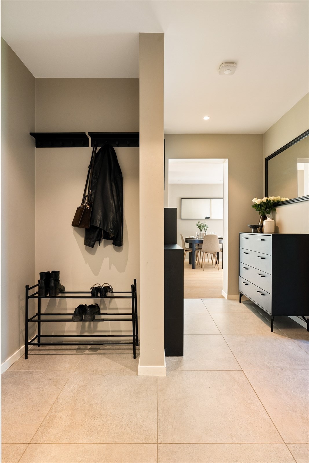 Stor, åpen gang/entre med delikate 60x60 fliser på gulv. Entreen gir et rettmessig inntrykk av leilighetens standard. Galleribilde