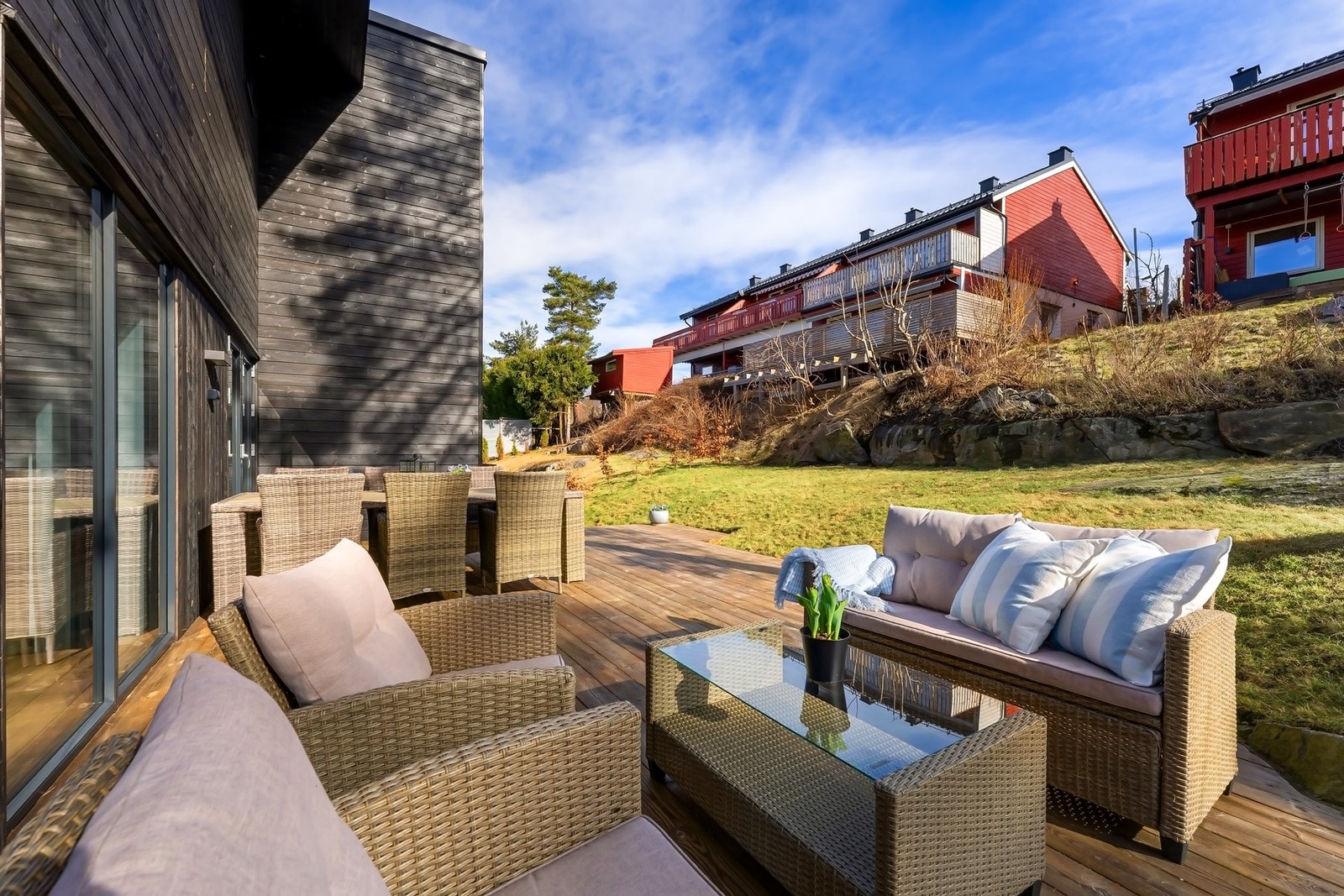 Barnvennlig og skjermet uteområde med terrasse, gressplen og beplantninger Galleribilde