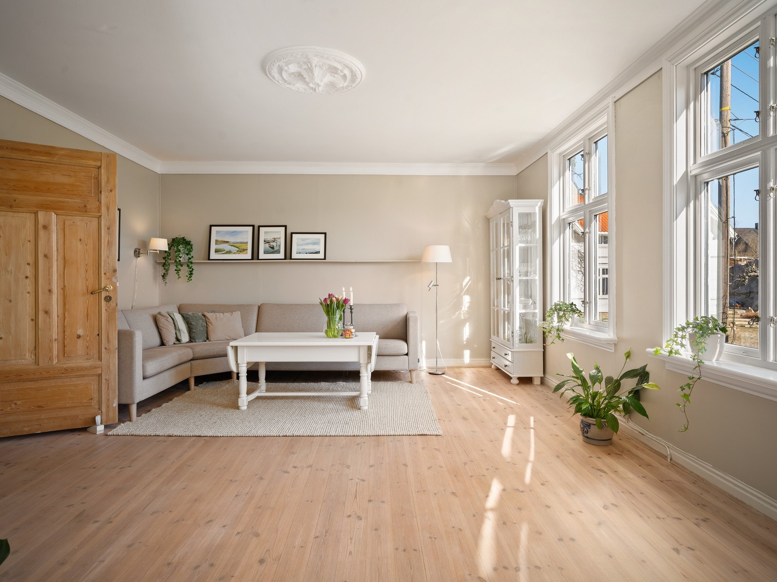 Store vinduer slipper inn rikelig med dagslys i boligens oppholdsrom. Orignial strekt tak fra 1904 med rosett. Galleribilde