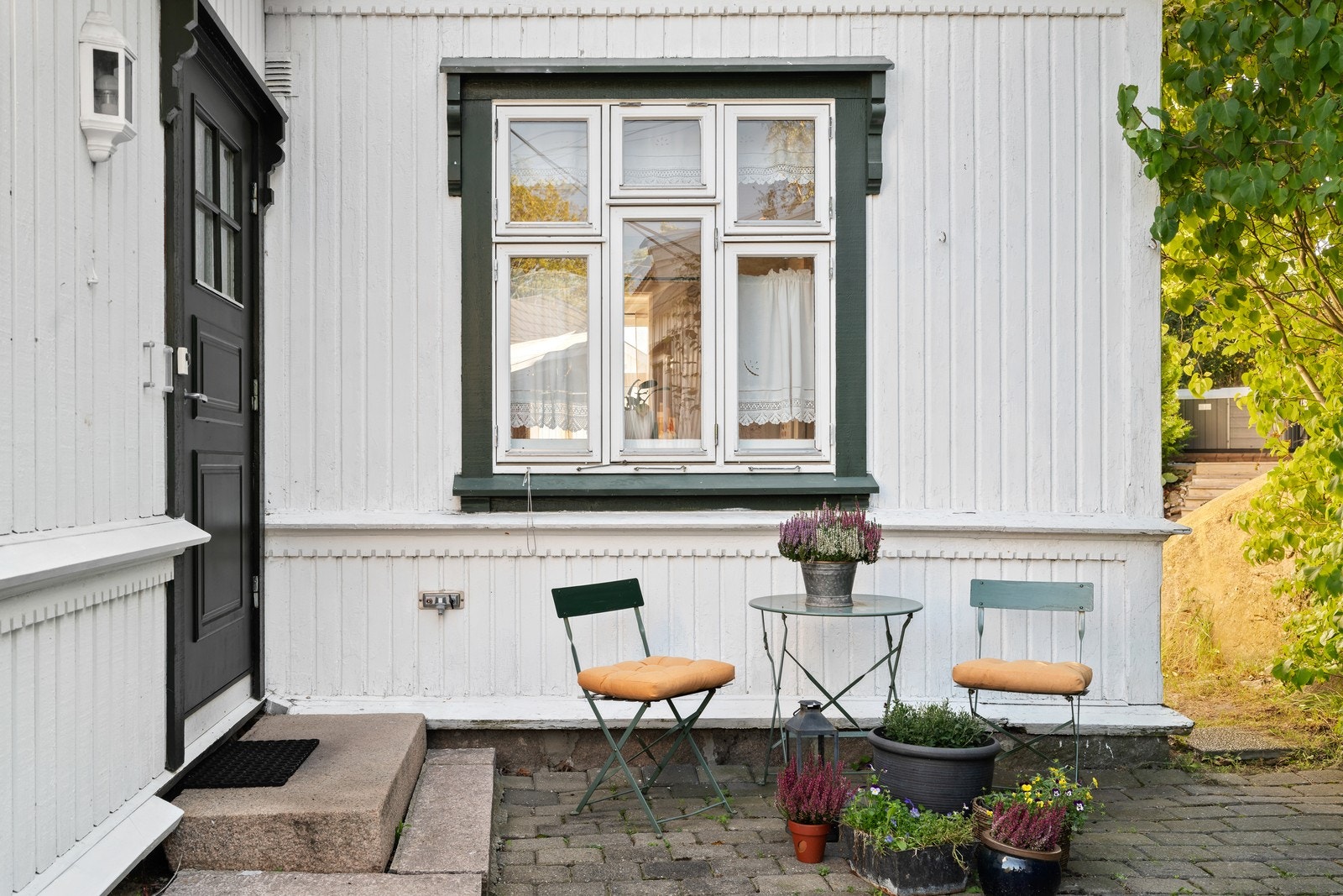 Et koselig inngangsparti ønsker deg velkommen. Bygningen har malte trevinduer i tidsriktig stil og en malt hovedytterdør. Galleribilde