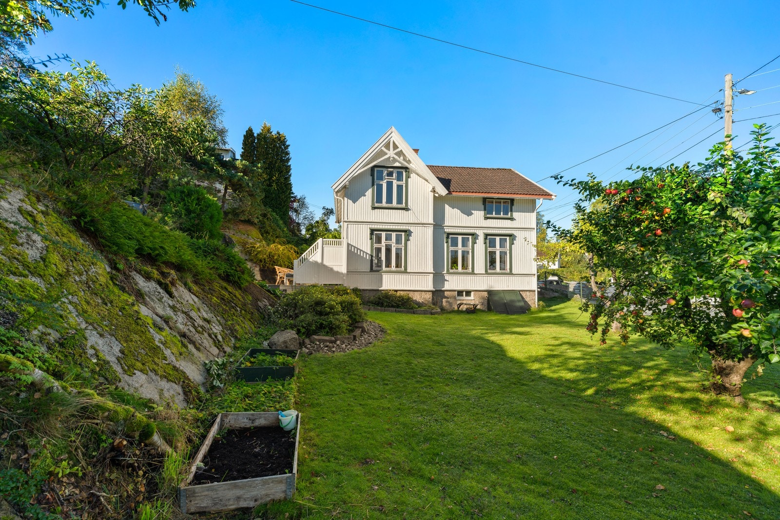 Hagen er inngjerdet og velstelt. Pent beplantet med frukttrær. Galleribilde